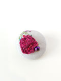 Decorative burgundy flower brooch on grey background