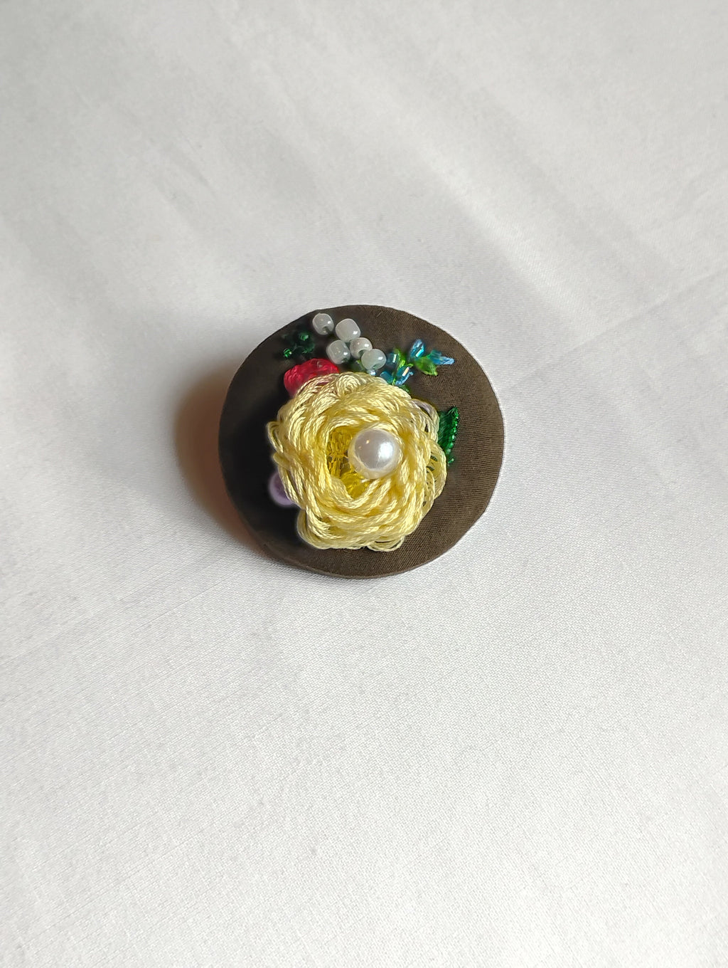 Decorative yellow flower brooch on olive background