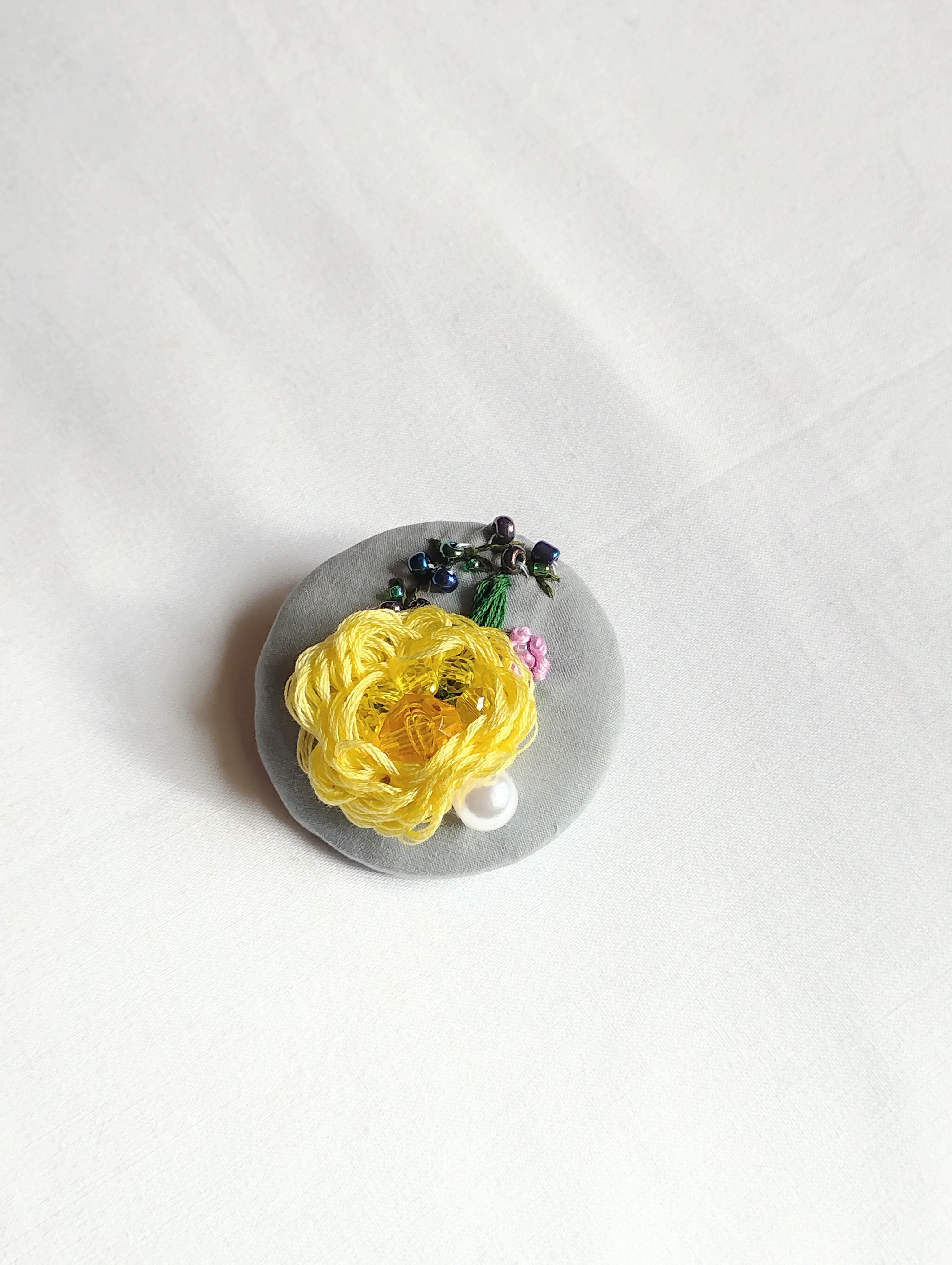 Decorative yellow flower brooch on grey background