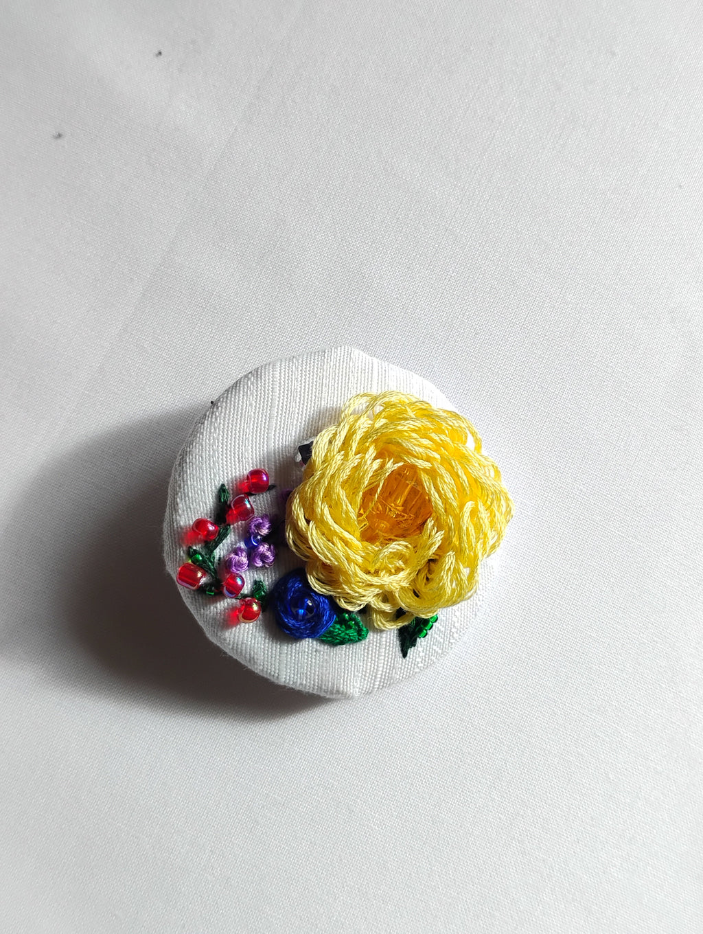 Decorative yellow flower brooch on white textured background
