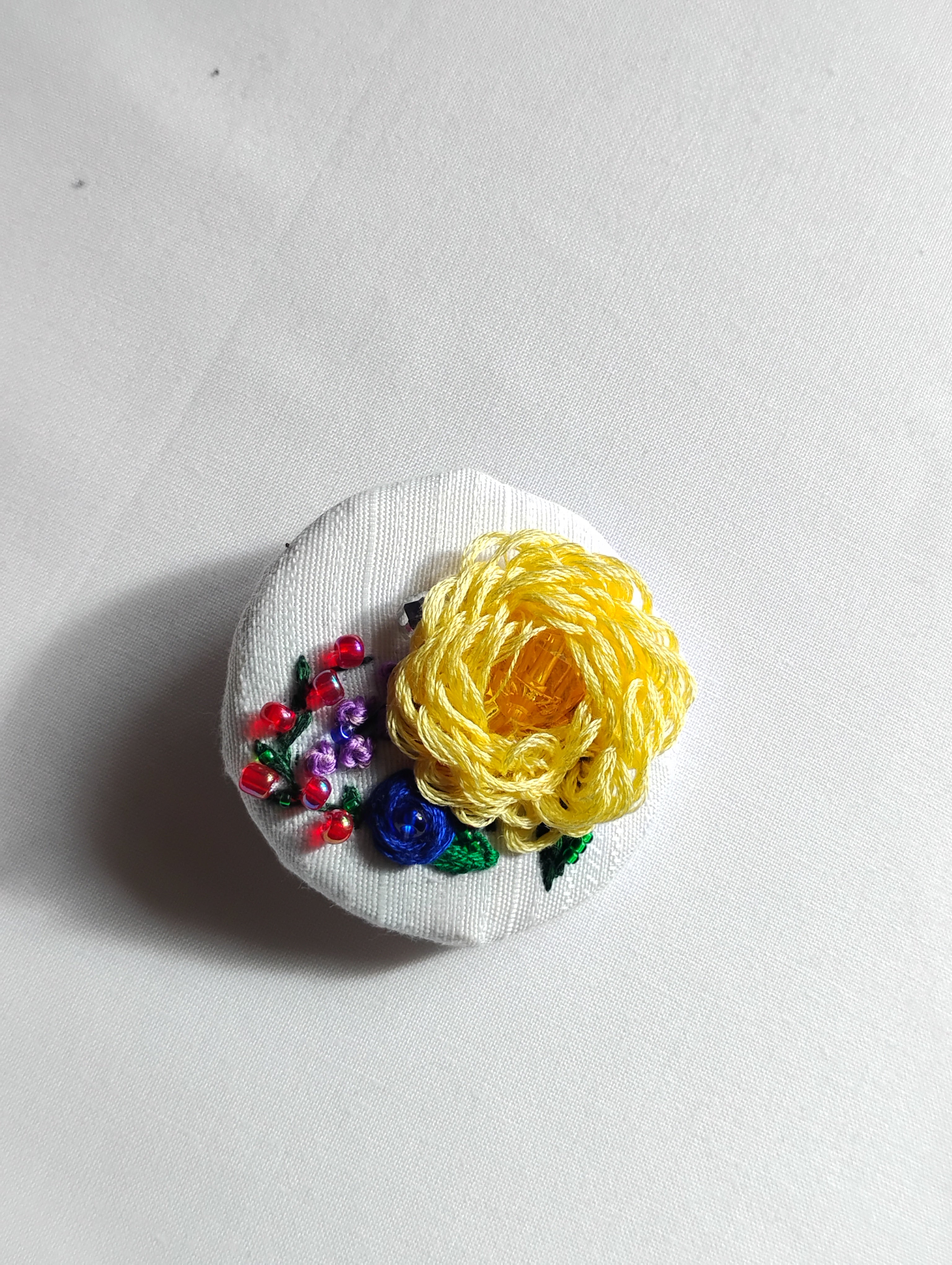Decorative yellow flower brooch on white textured background
