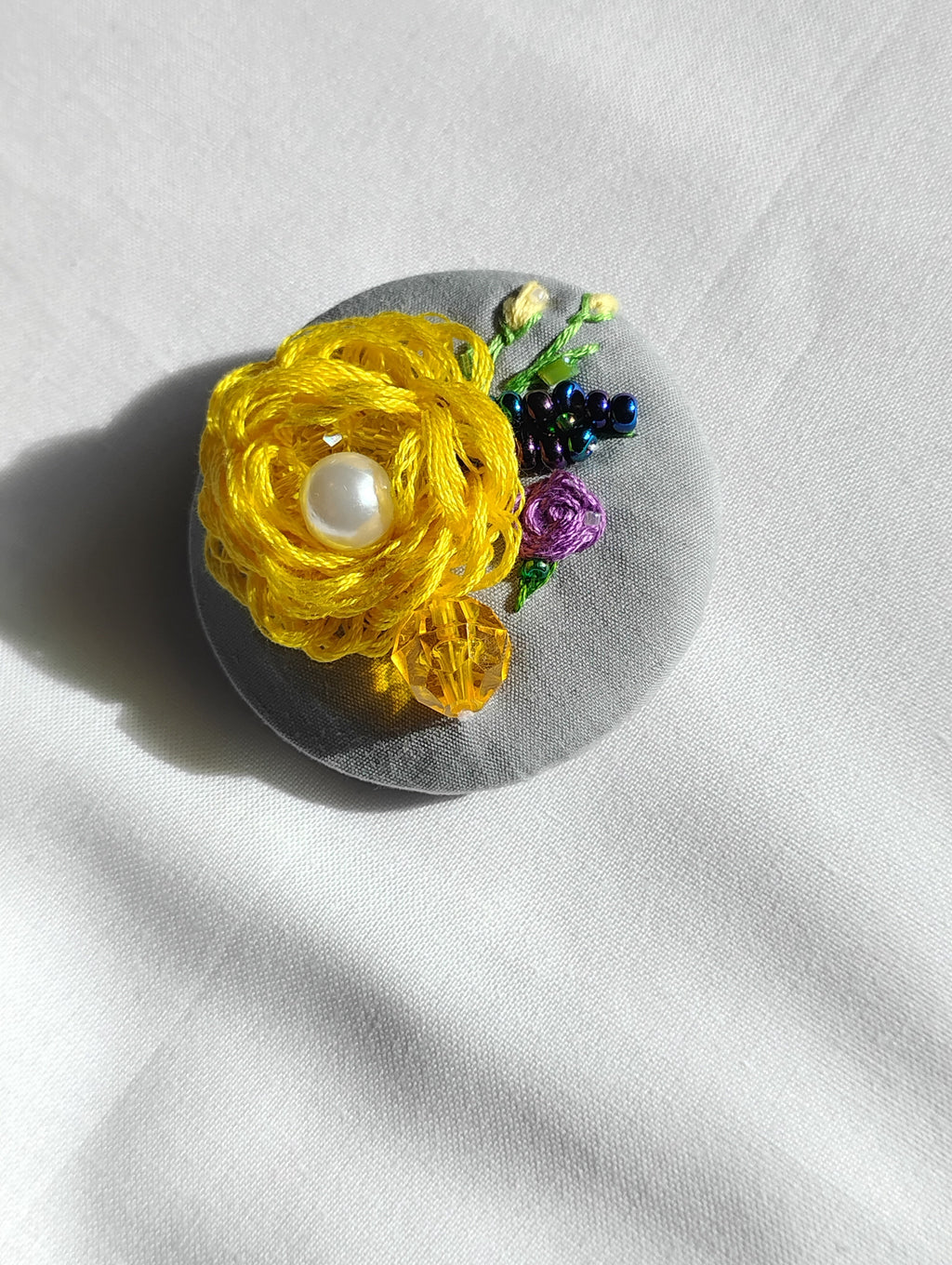 Decorative yellow flower brooch on grey background