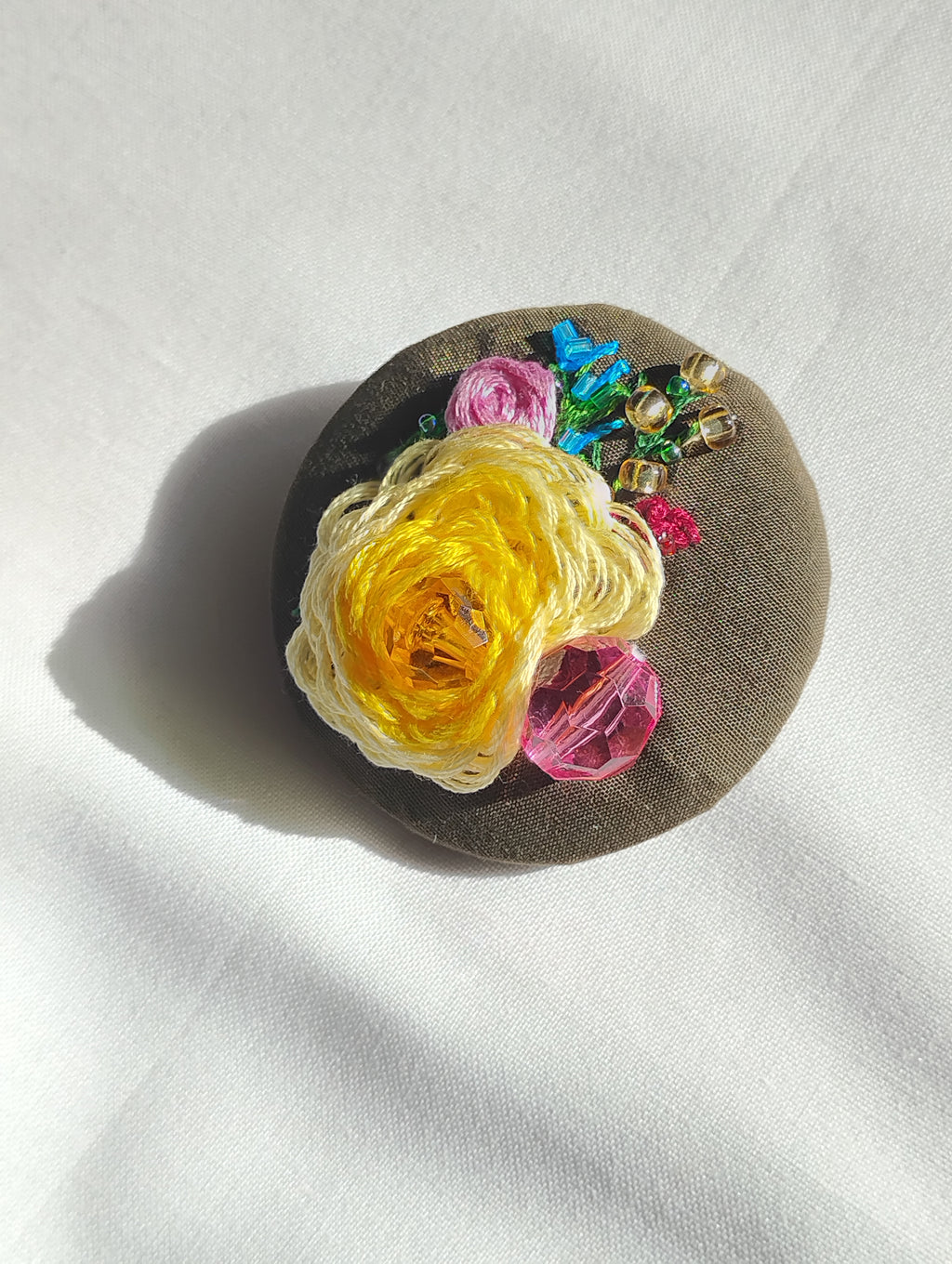 Decorative yellow flower brooch on olive background