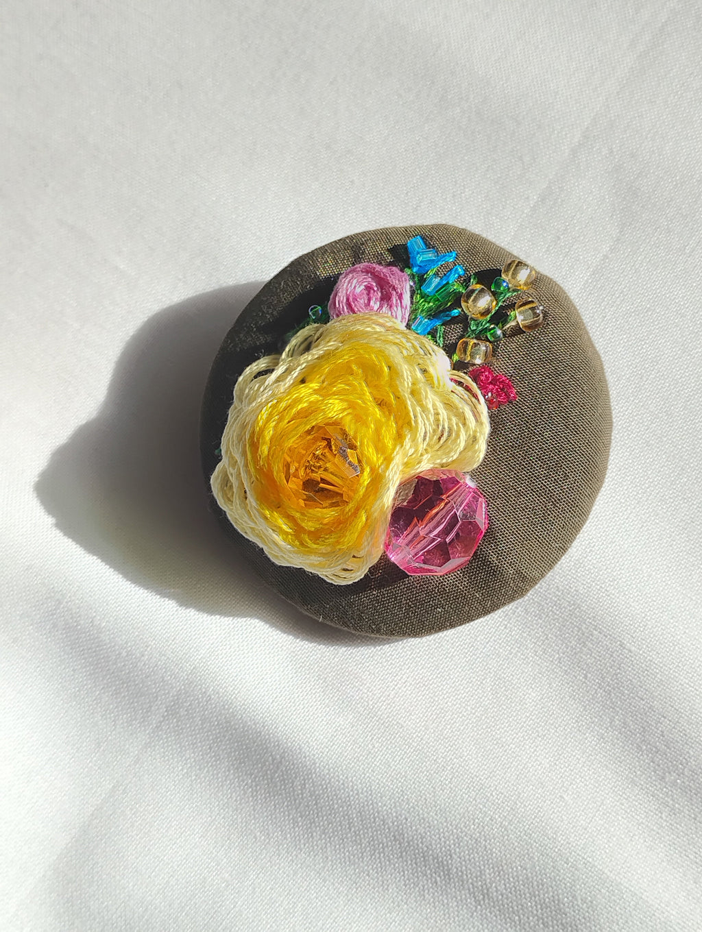 Decorative yellow flower brooch on olive background