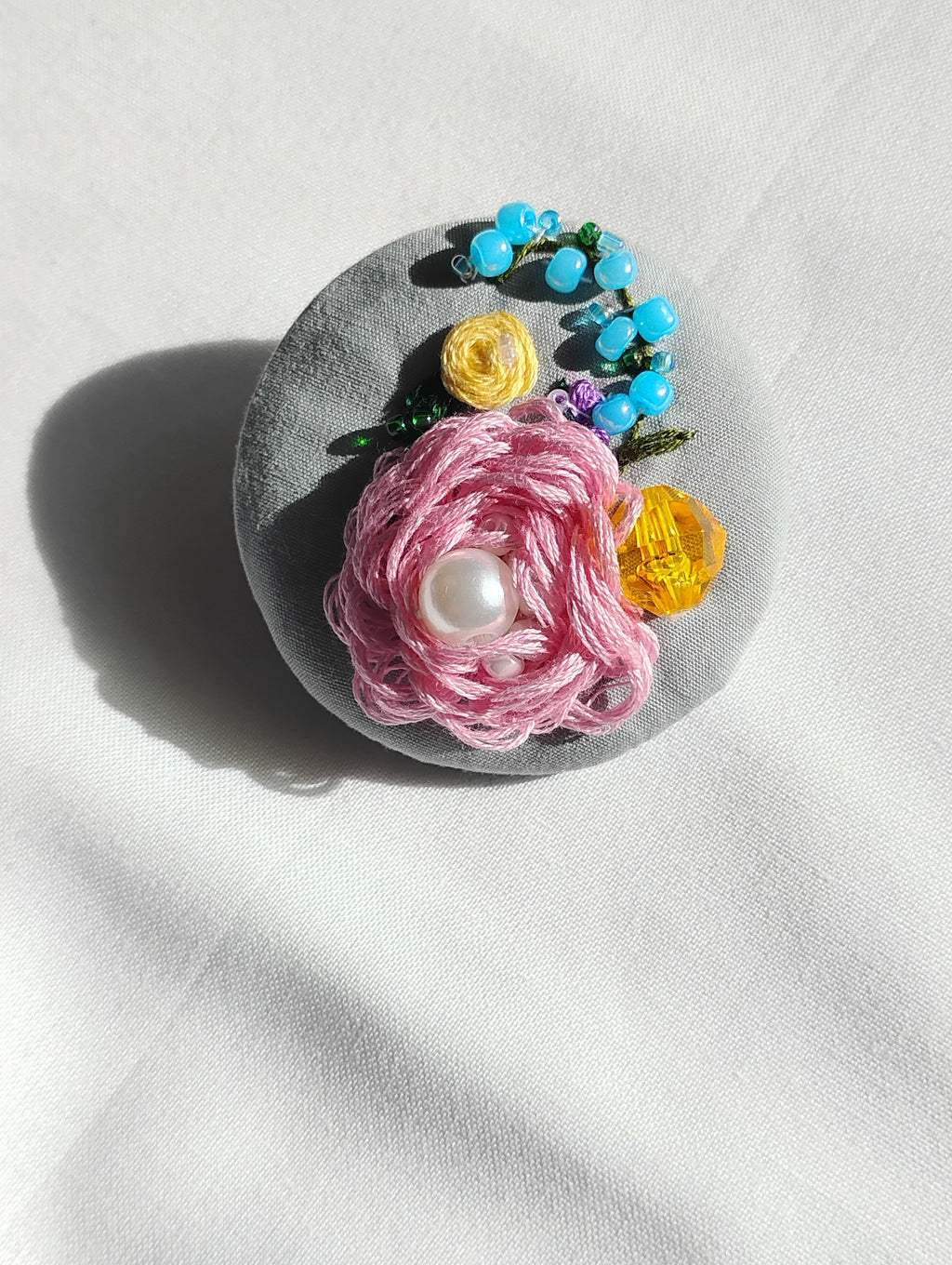 Decorative pink flower brooch on grey background