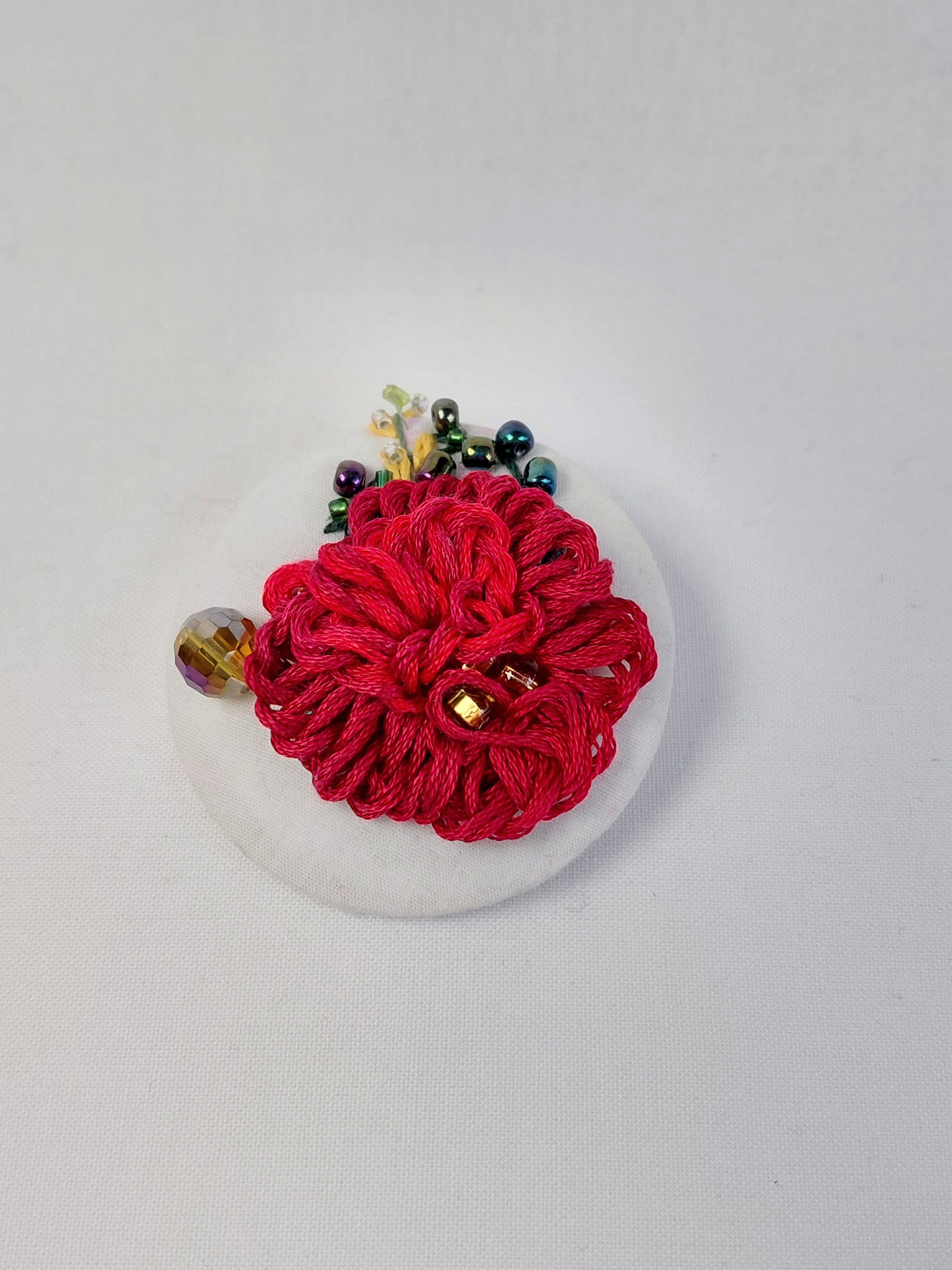 Decorative burgundy flower brooch on white background
