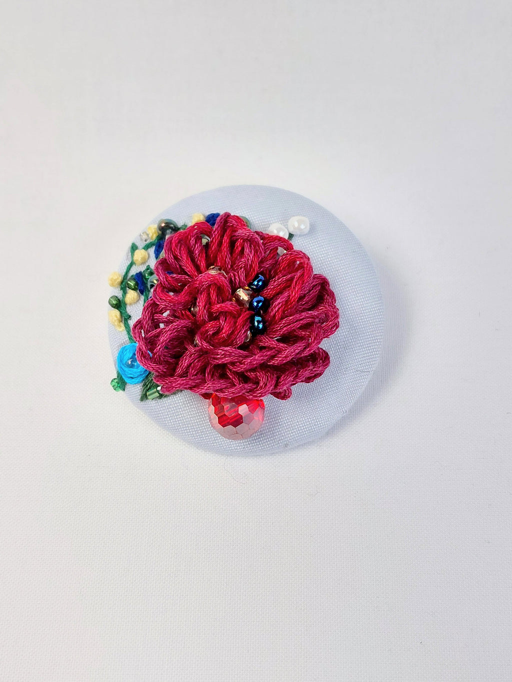 Decorative burgundy flower brooch on light blue background