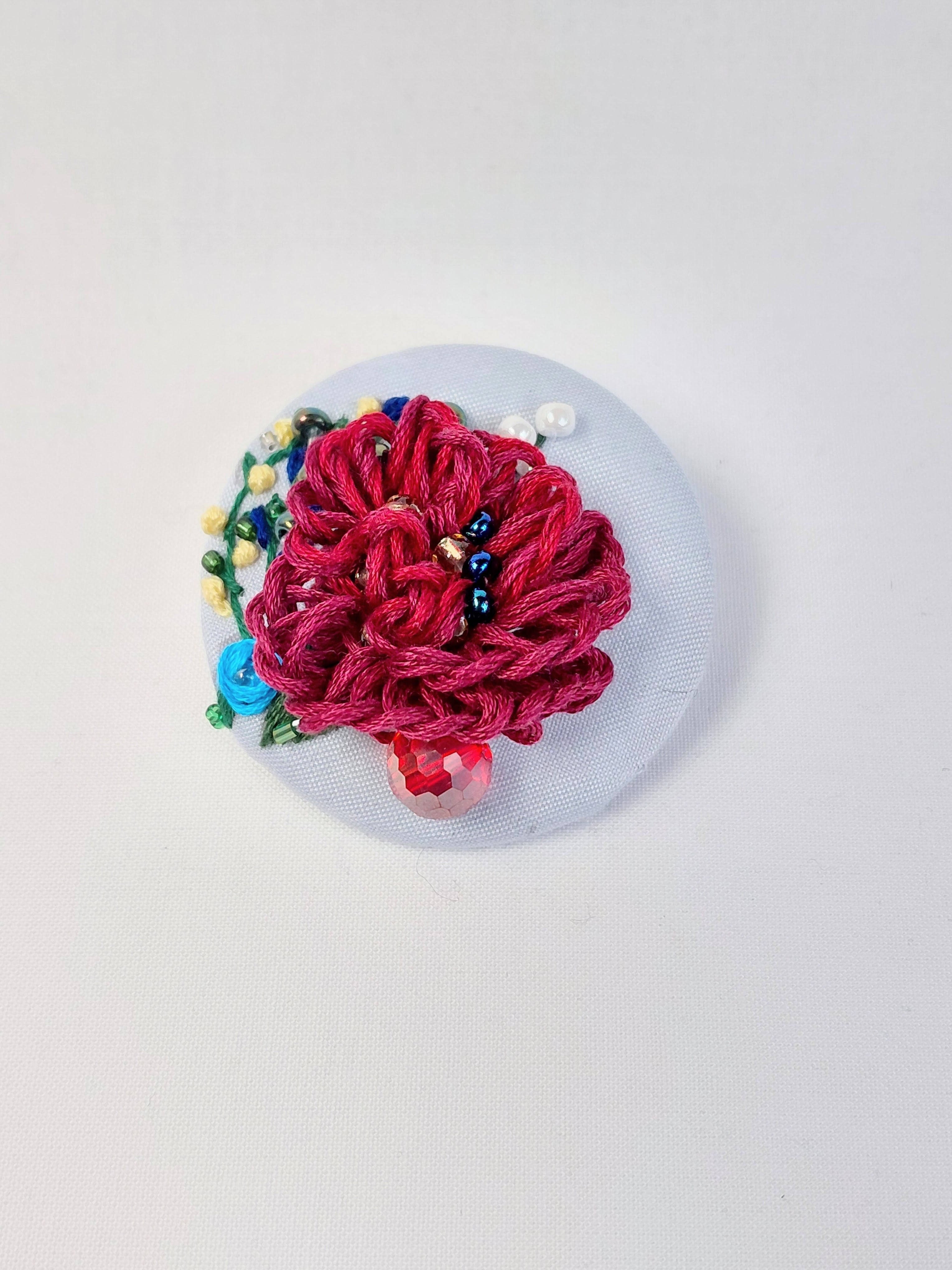 Decorative burgundy flower brooch on light blue background