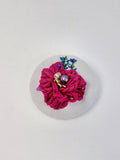 Decorative burgundy flower brooch on grey with specs background