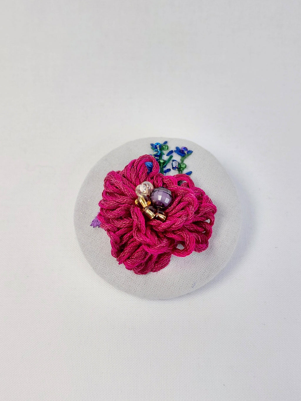 Decorative burgundy flower brooch on grey with specs background