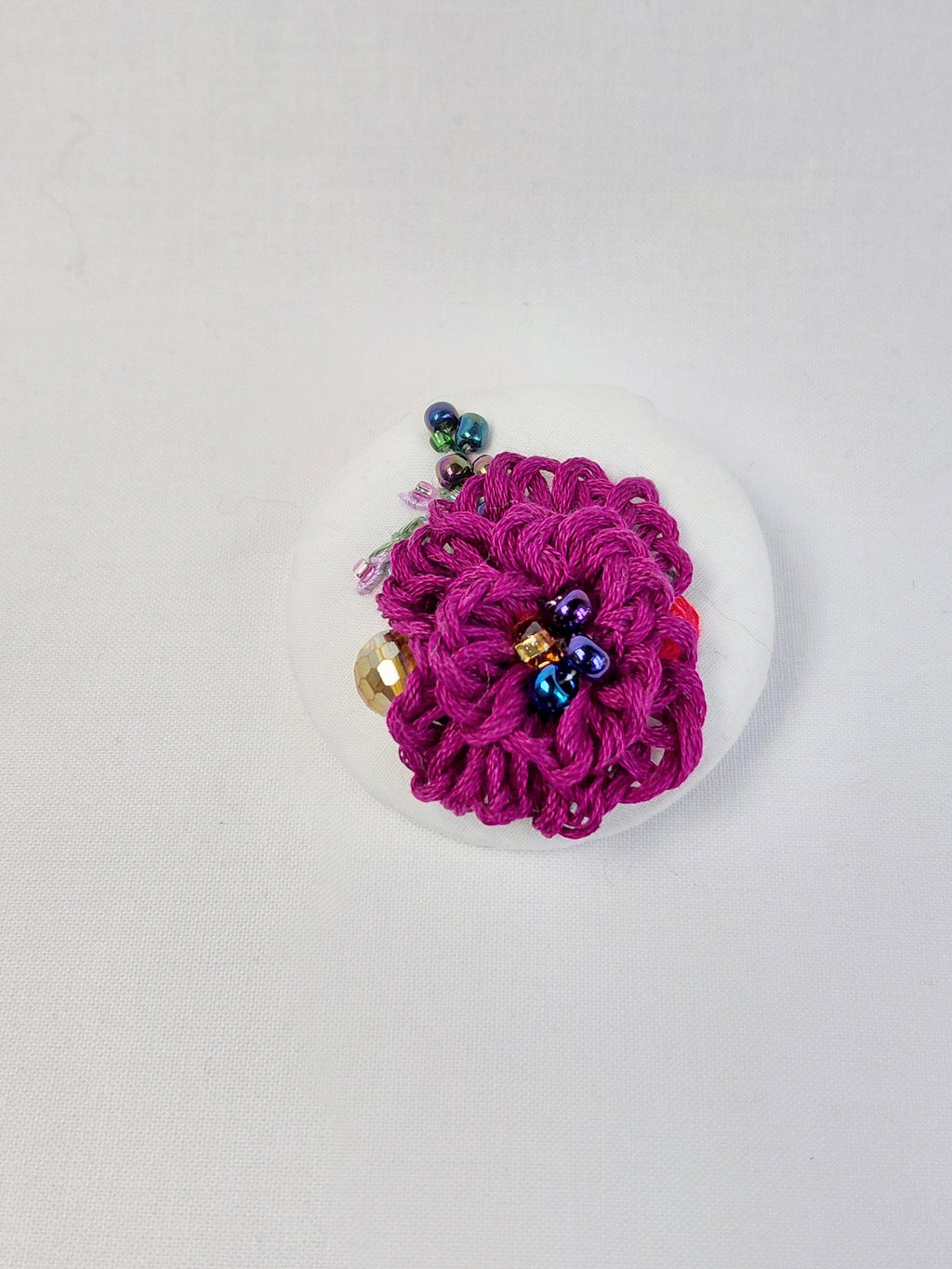 Decorative burgundy flower brooch on white background
