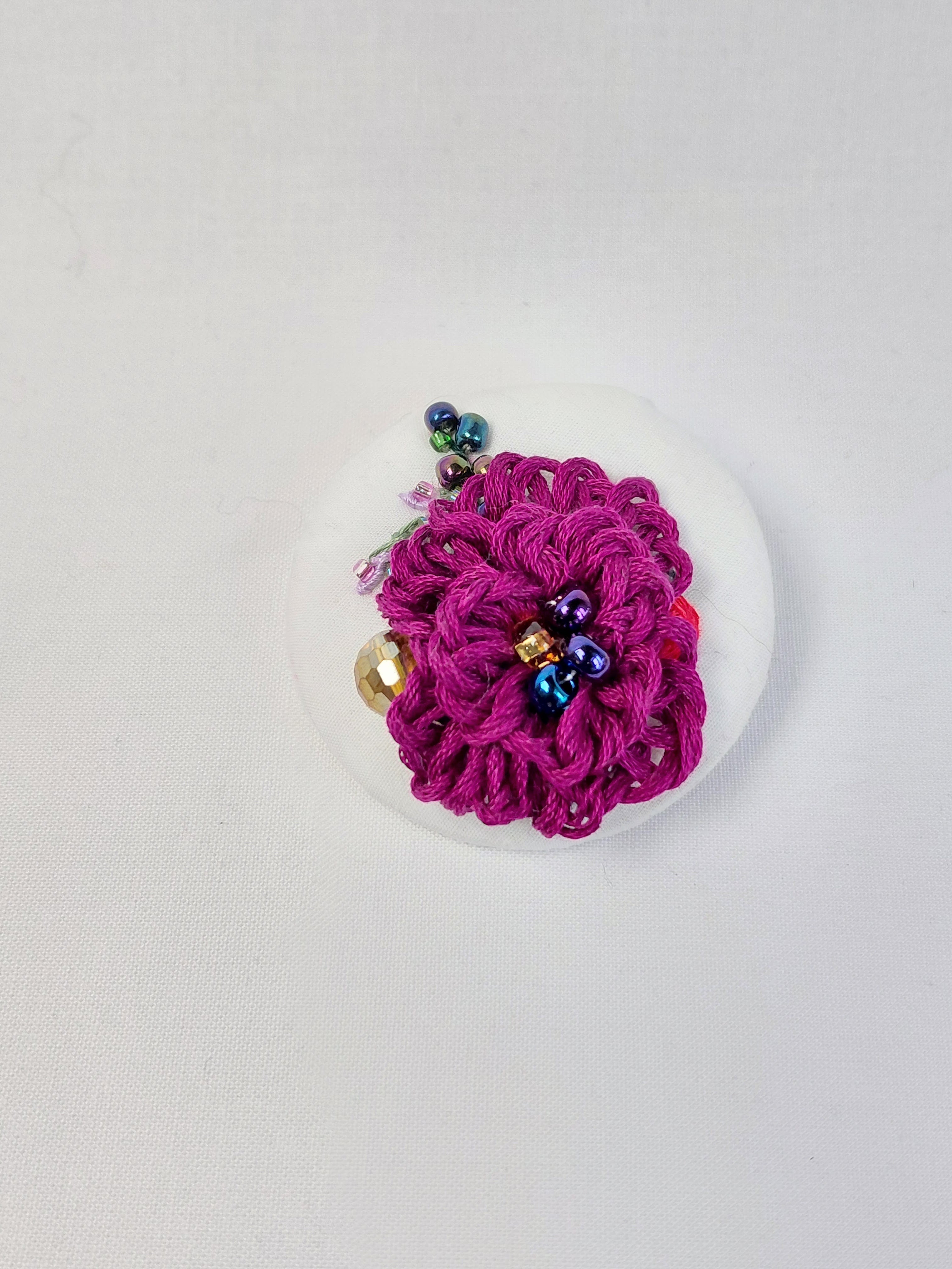Decorative burgundy flower brooch on white background
