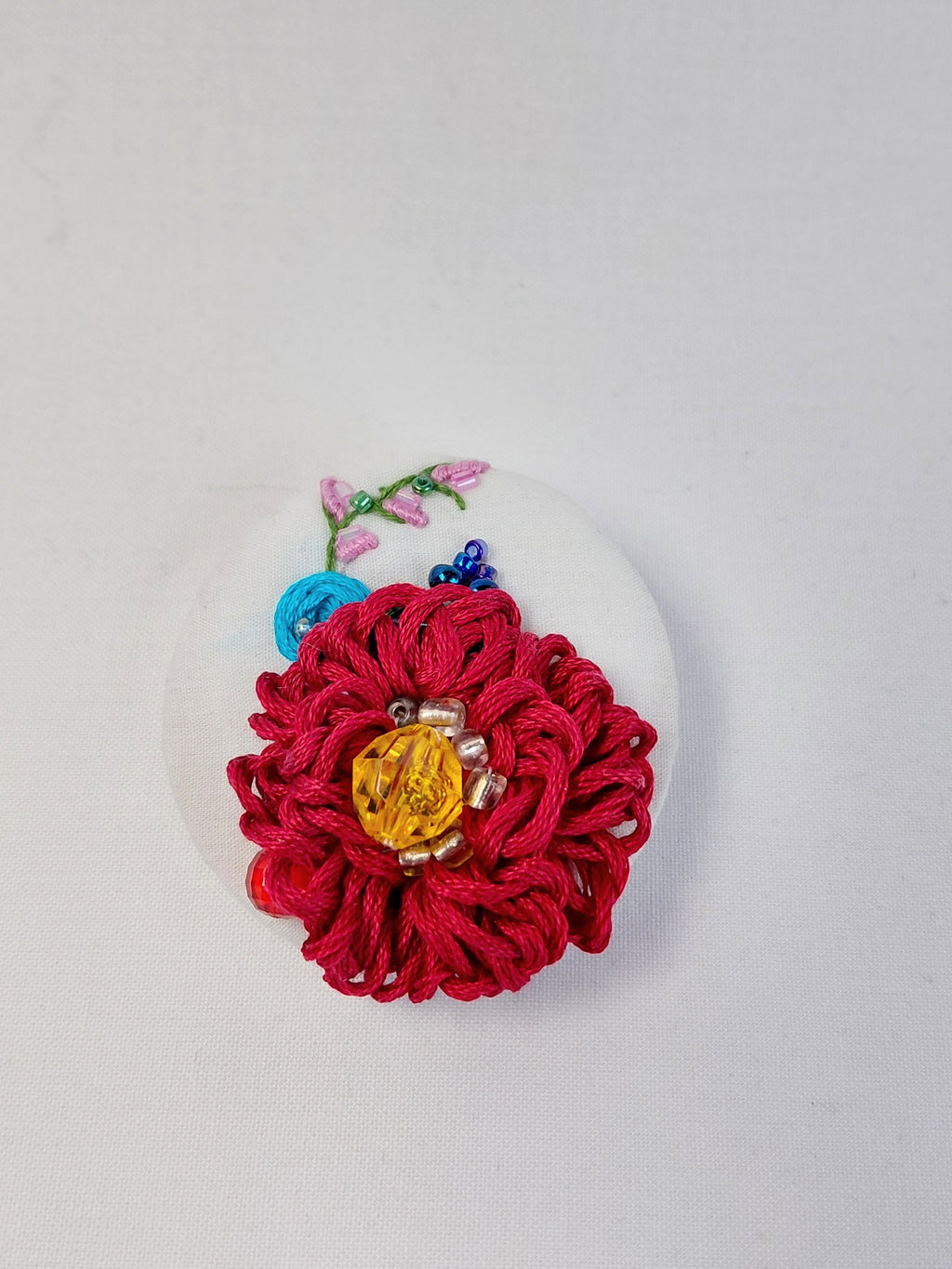 Decorative burgundy flower brooch on white background