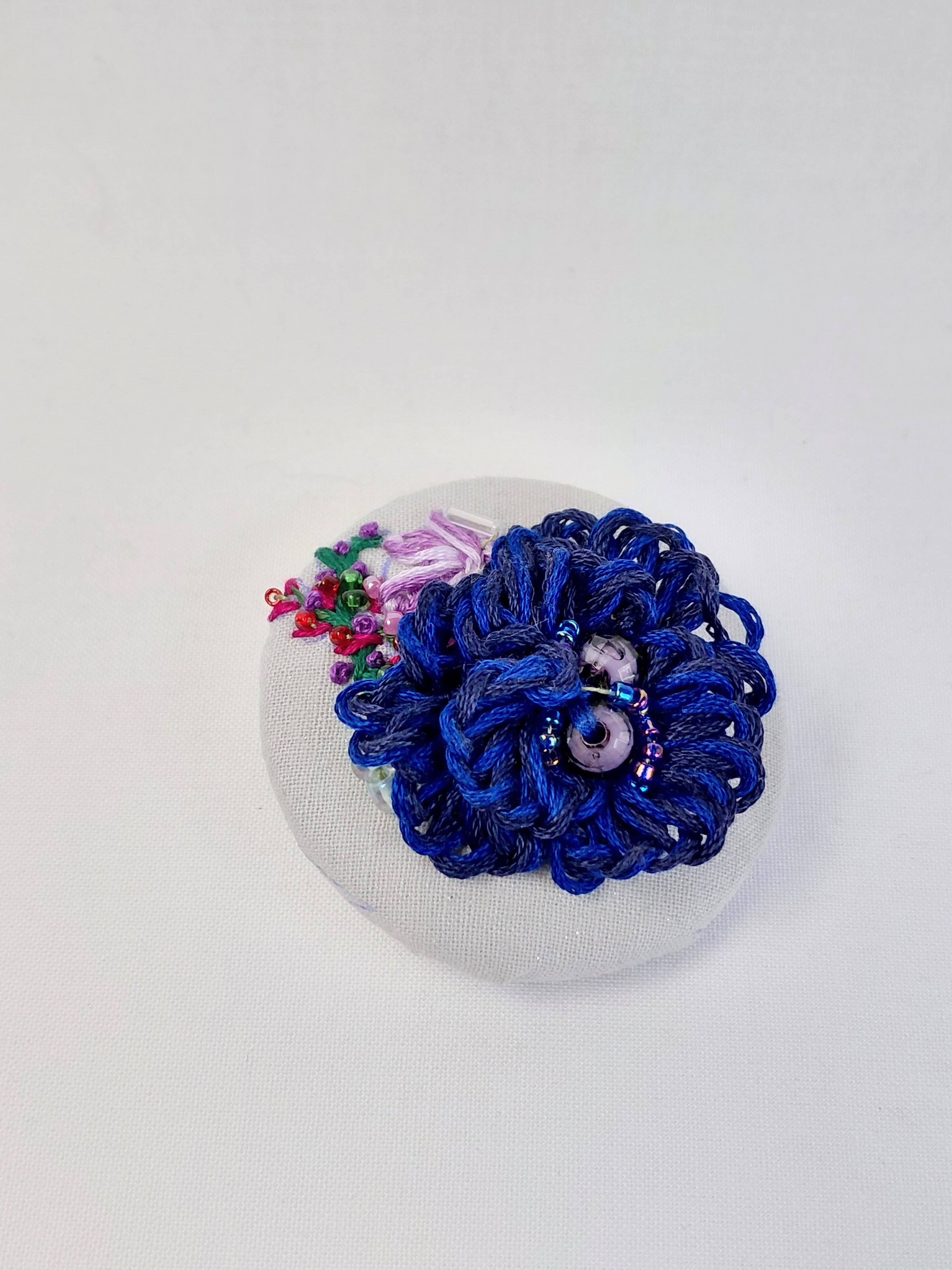 Decorative blue flower brooch on grey with specs background
