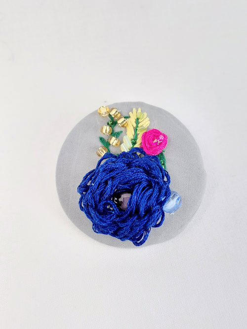Decorative blue flower brooch on grey background