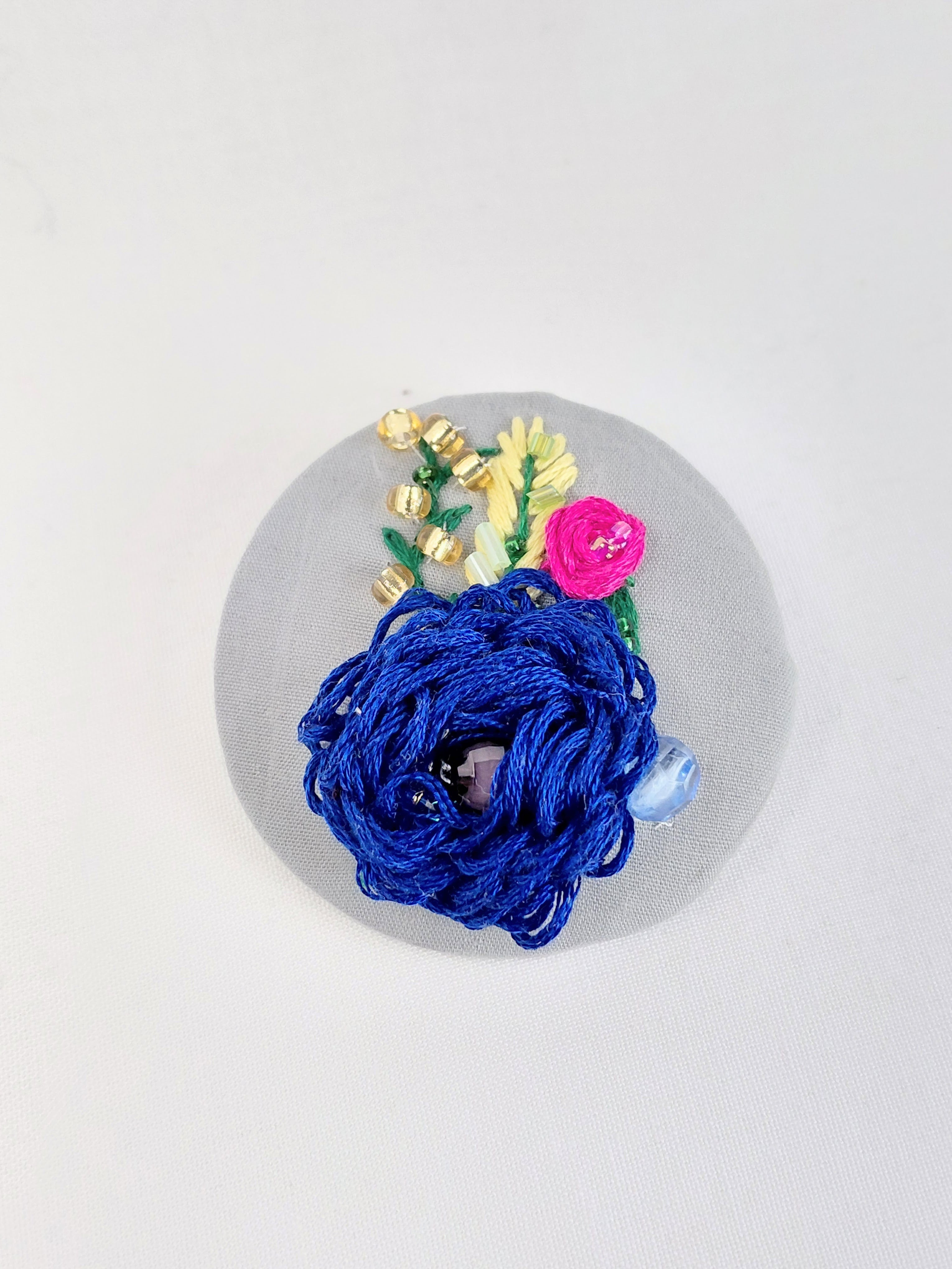 Decorative blue flower brooch on grey background