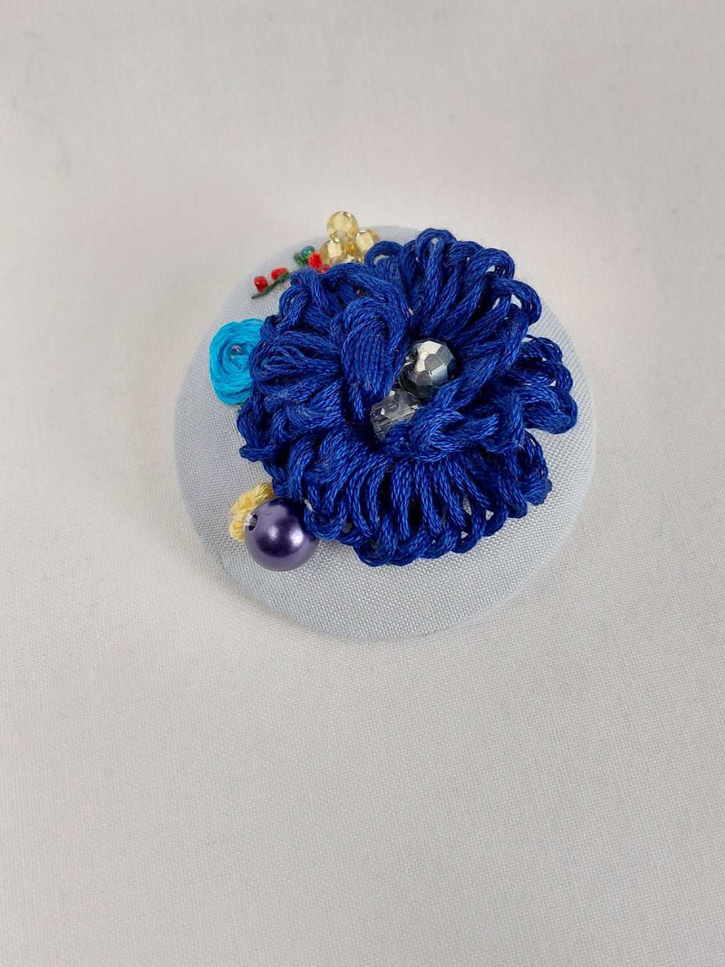 Decorative blue flower brooch on light blue background
