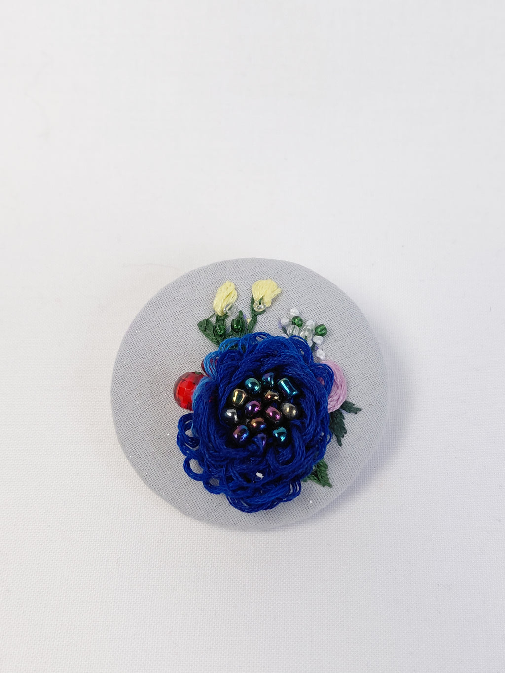 Decorative blue flower brooch on light blue with specs background