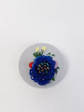 Decorative blue flower brooch on light blue with specs background