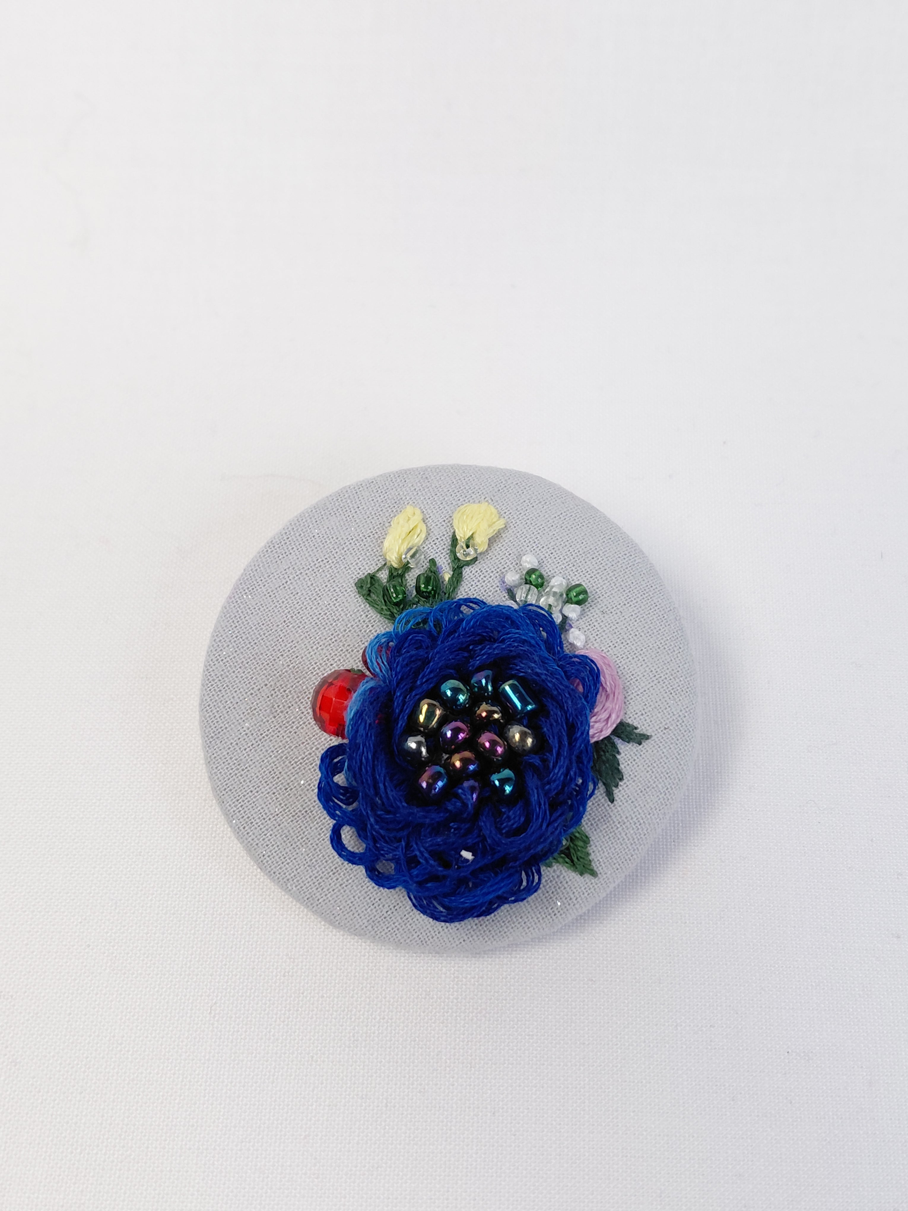 Decorative blue flower brooch on light blue with specs background