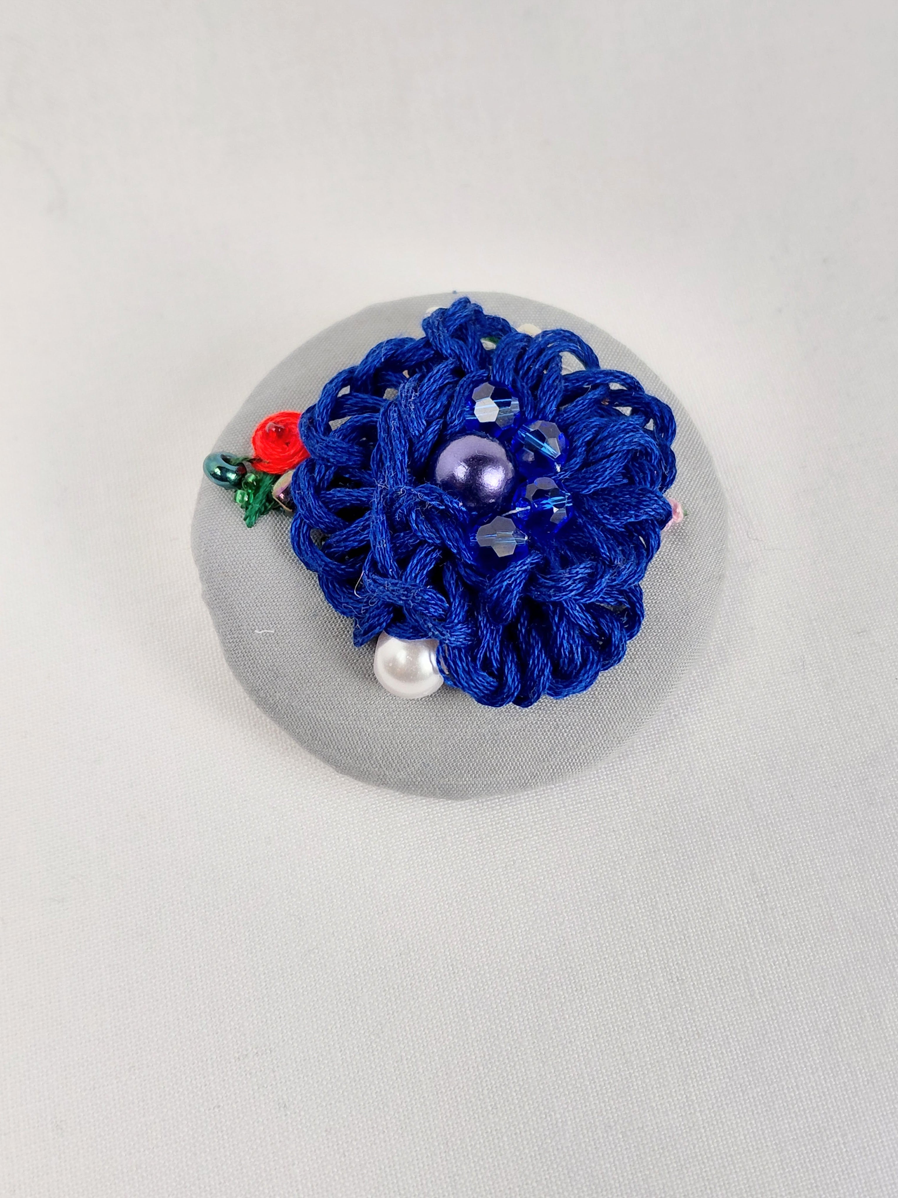 Decorative blue flower brooch on grey background