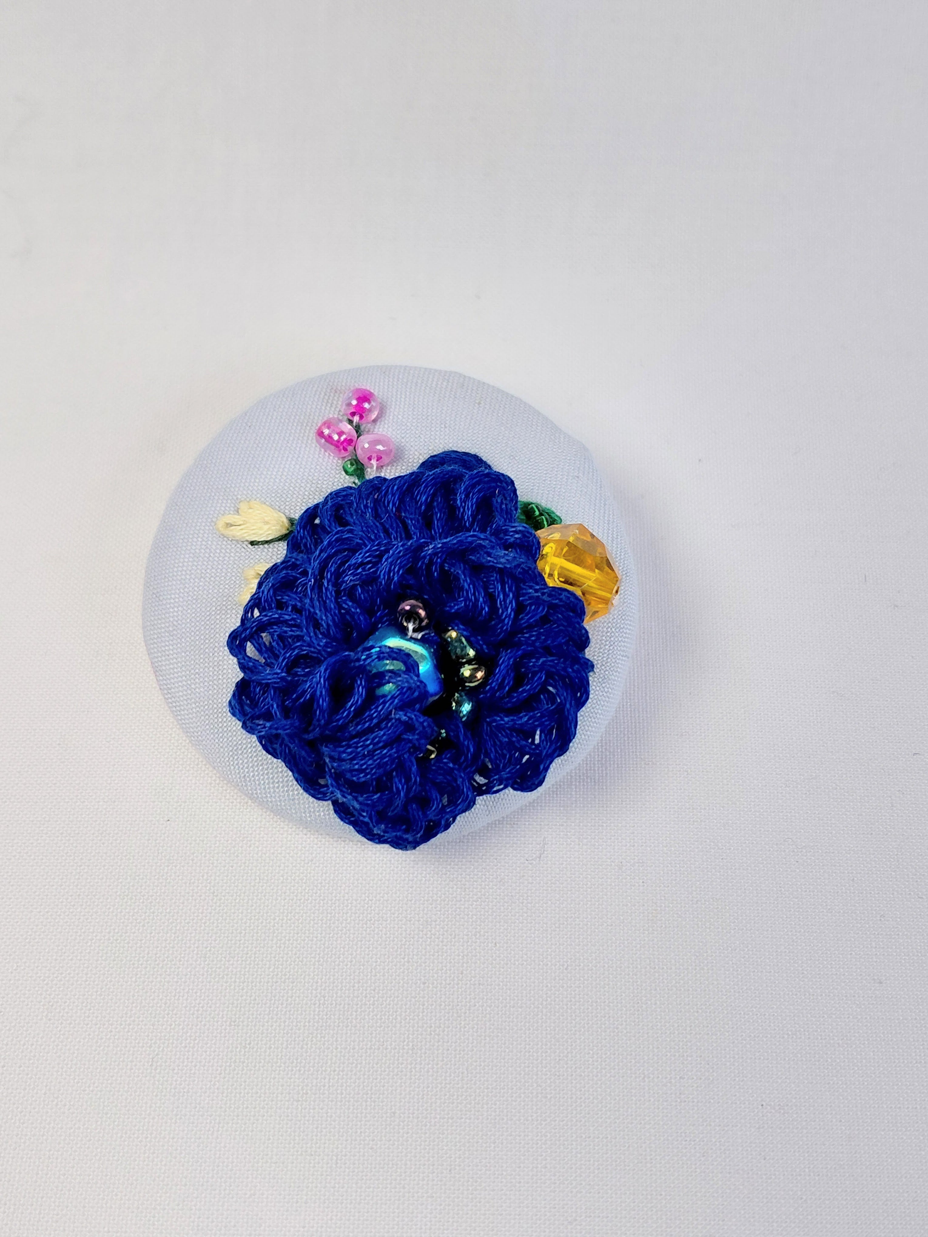 Decorative blue flower brooch on light blue background