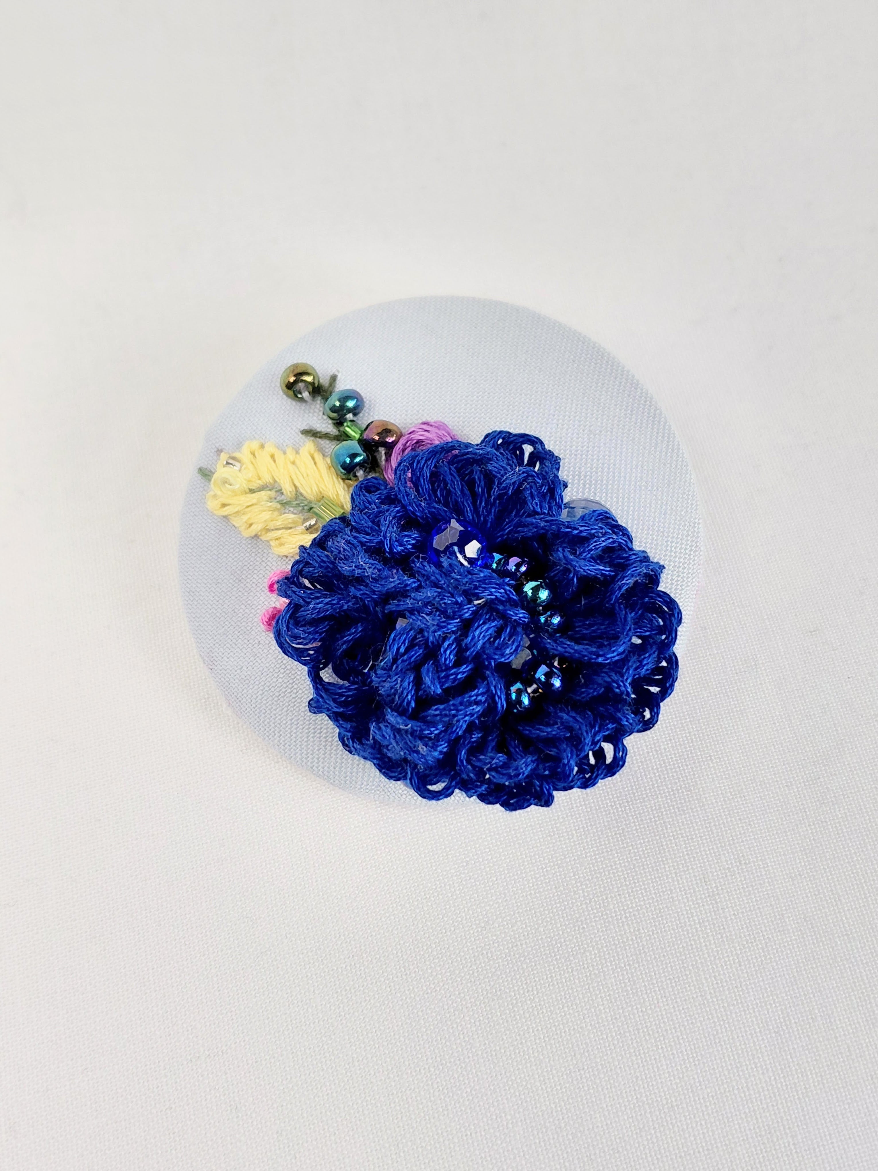 Decorative blue flower brooch on light blue background