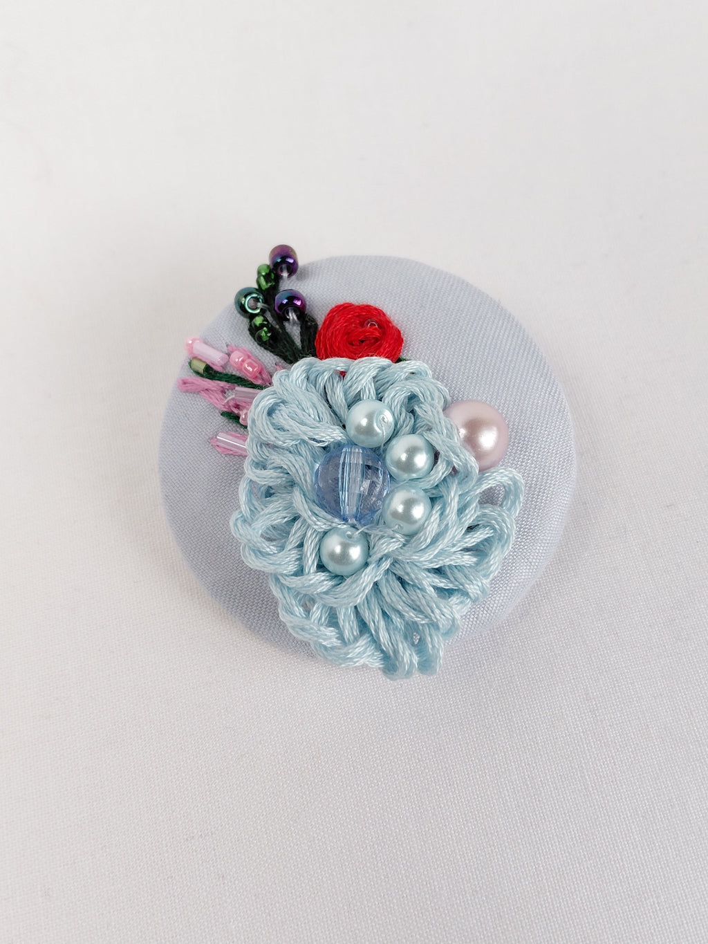 Decorative blue flower brooch on light blue background