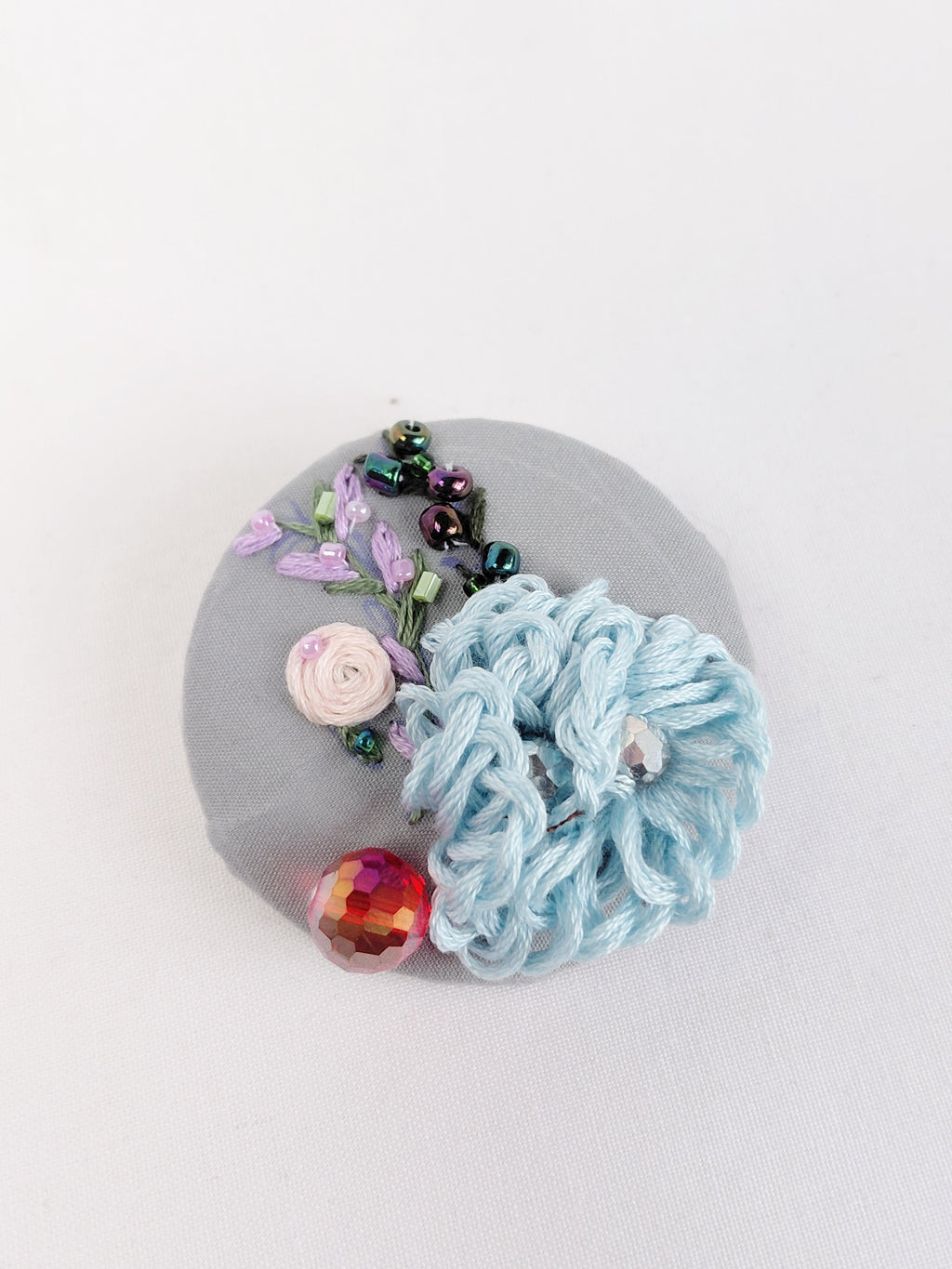 Decorative blue flower brooch on grey background