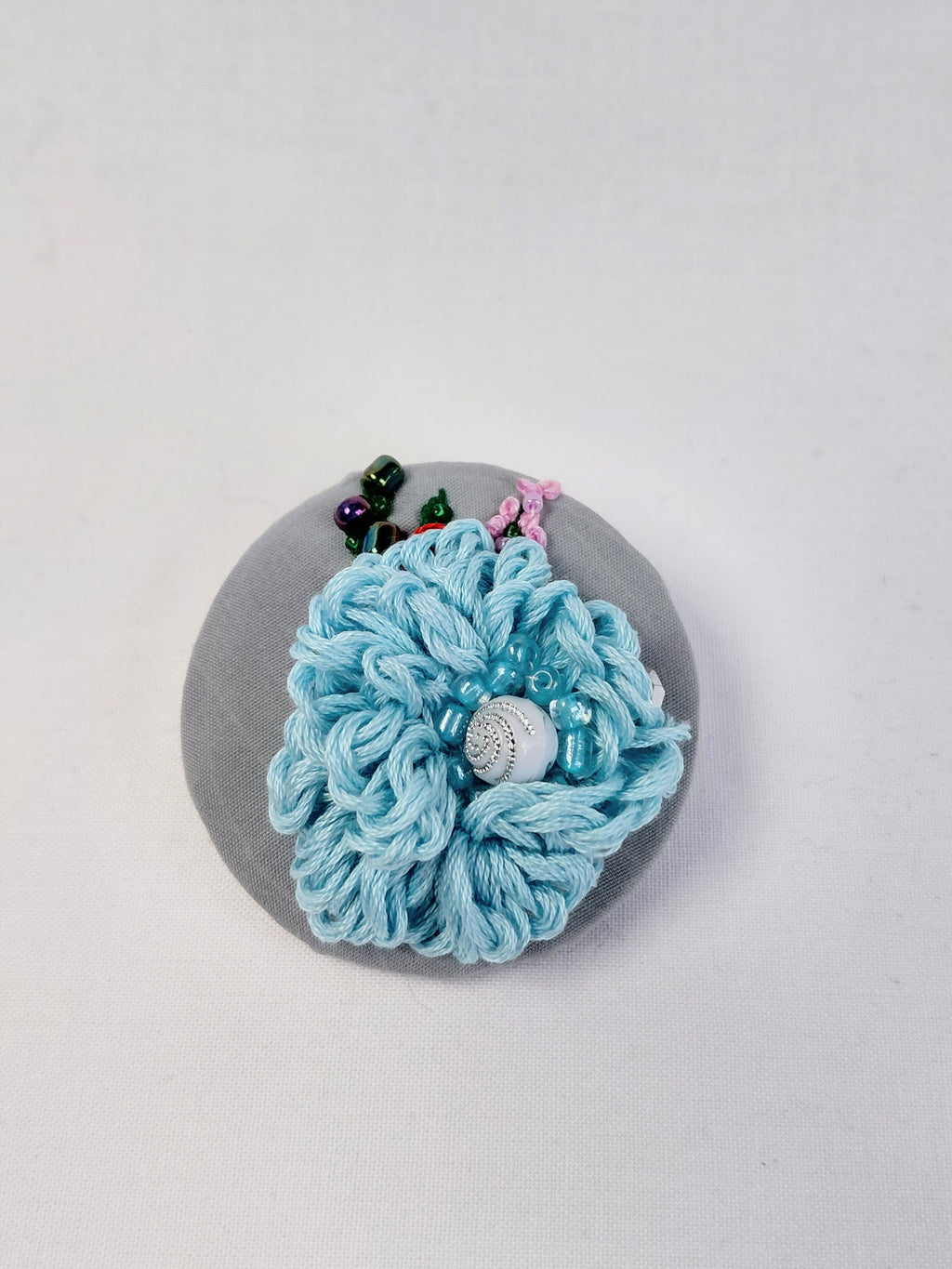 Decorative blue flower brooch on grey background