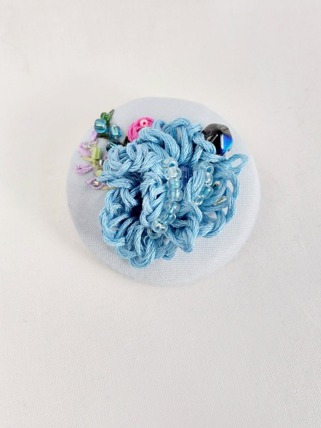 Decorative blue flower brooch on light blue background