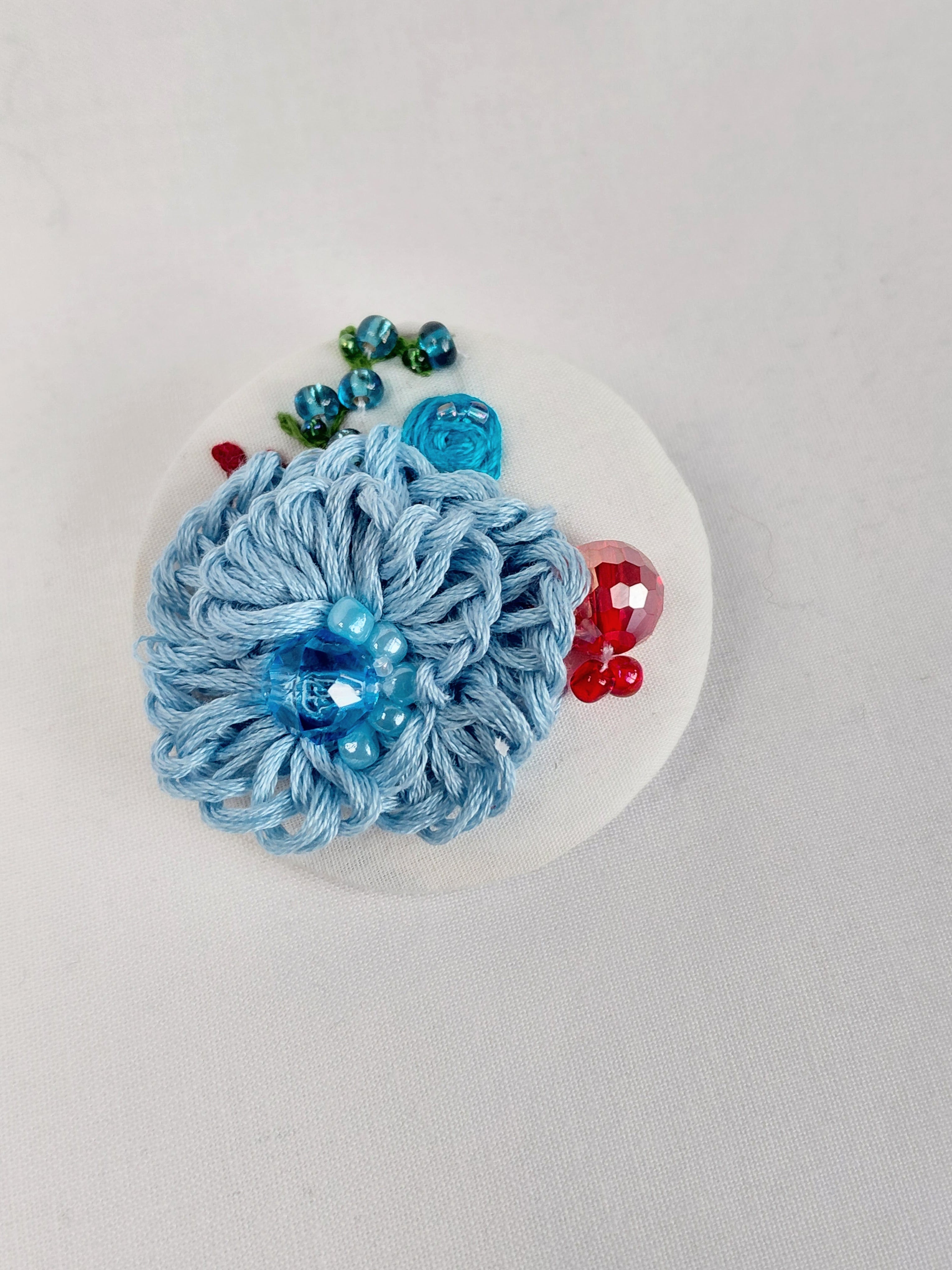 Decorative blue flower brooch on white background