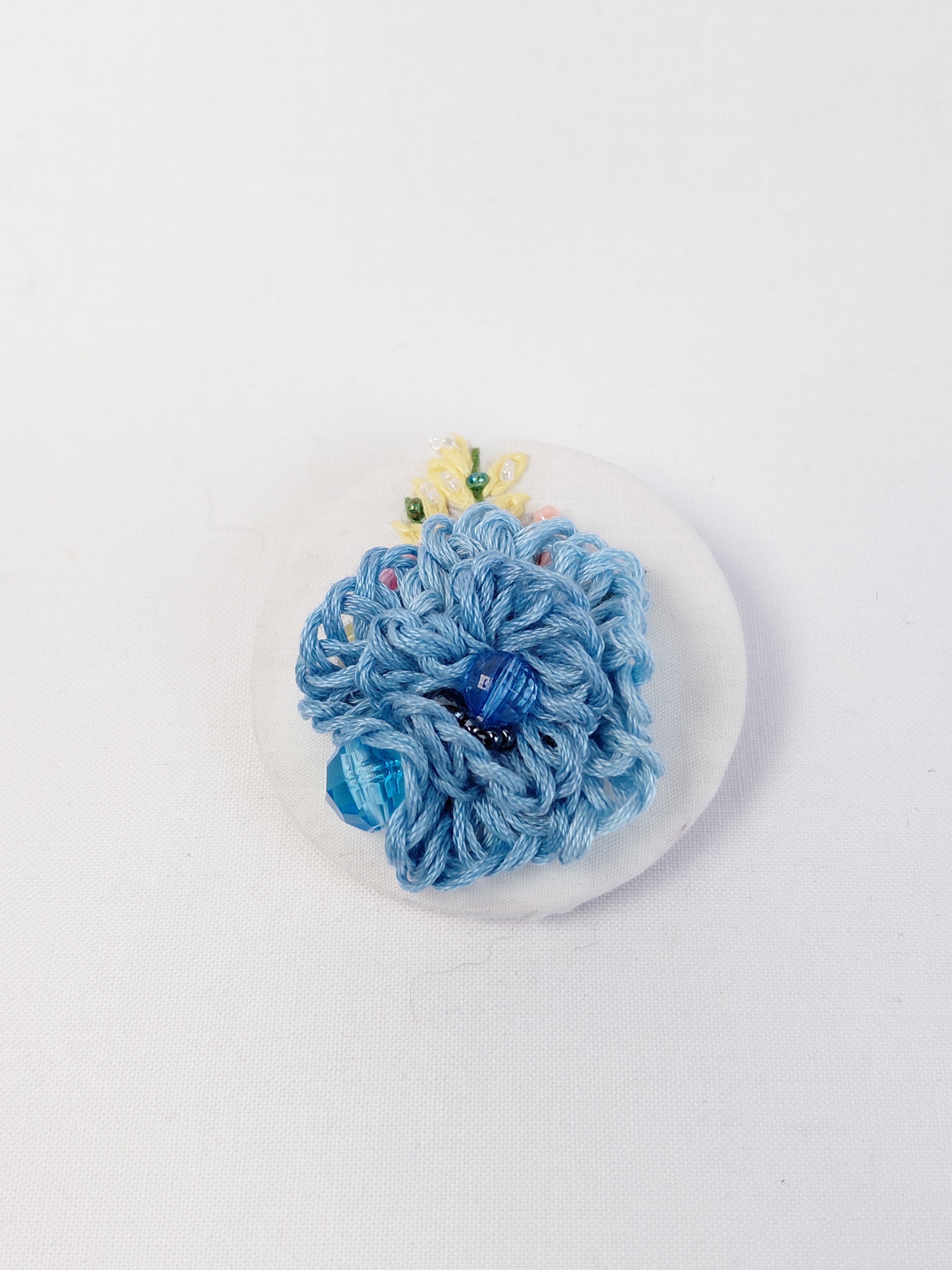 Decorative blue flower brooch on white background
