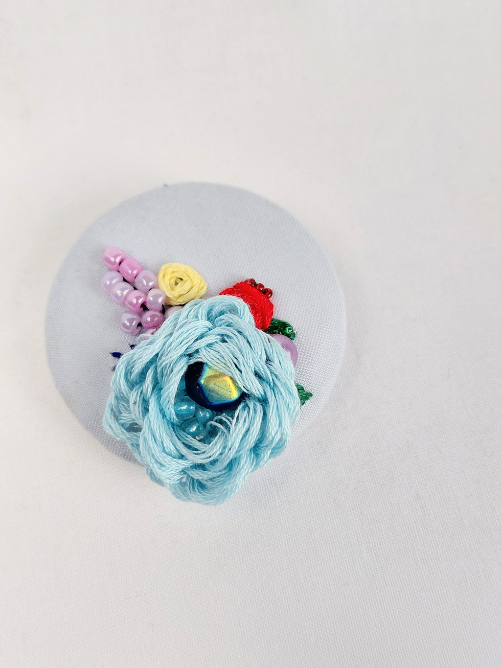 Decorative blue flower brooch on light blue background