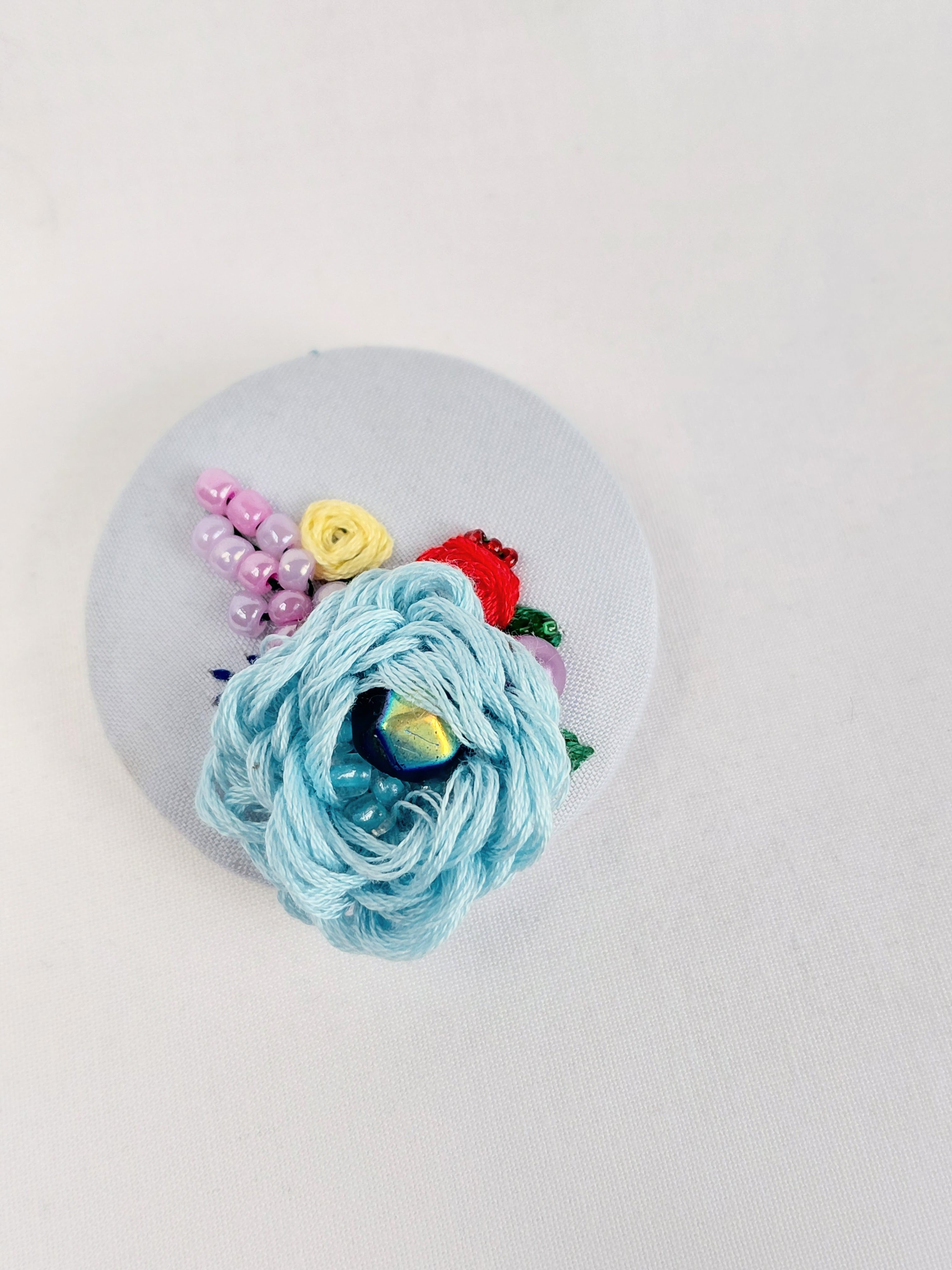 Decorative blue flower brooch on light blue background