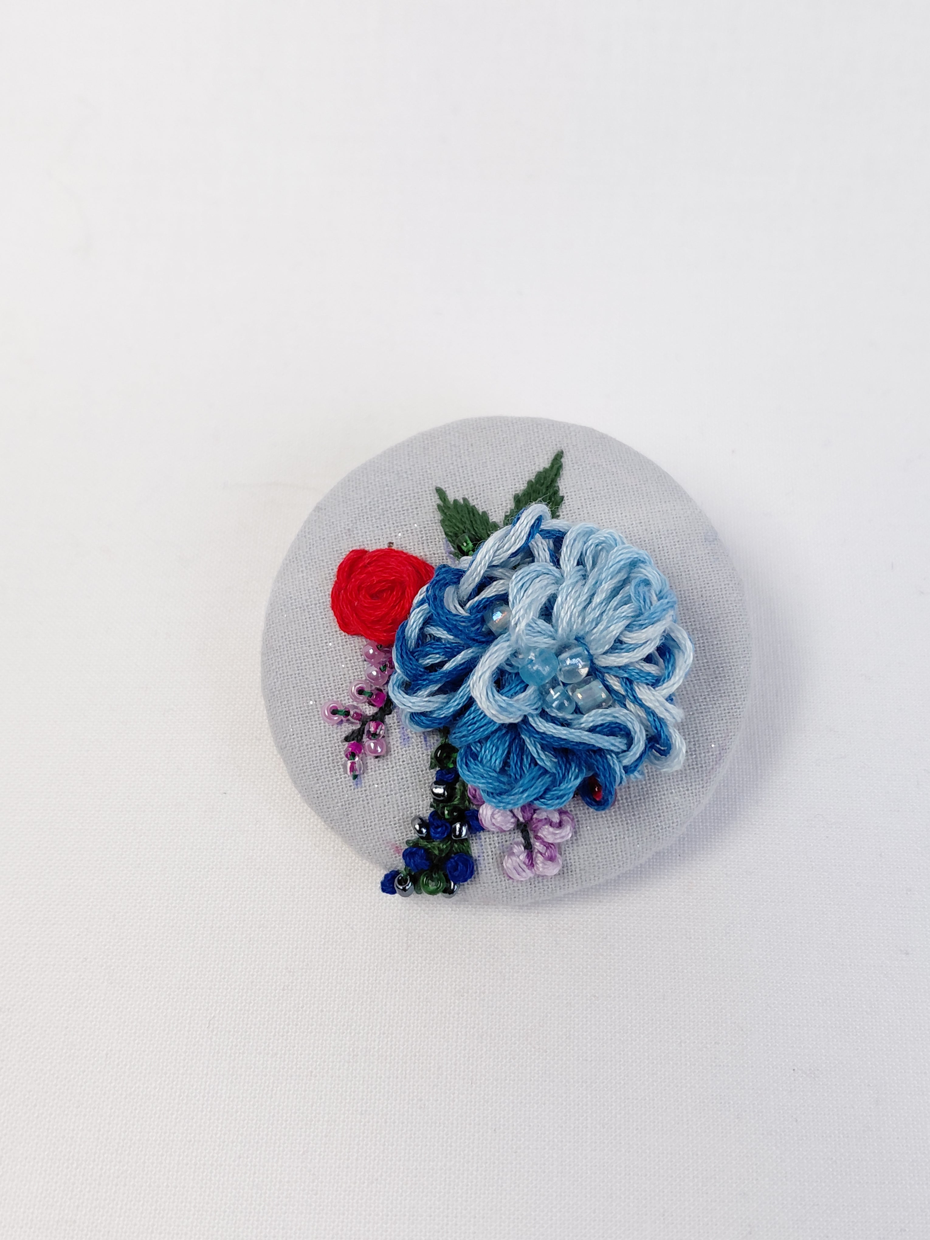 Decorative blue flower brooch on light blue with specs background