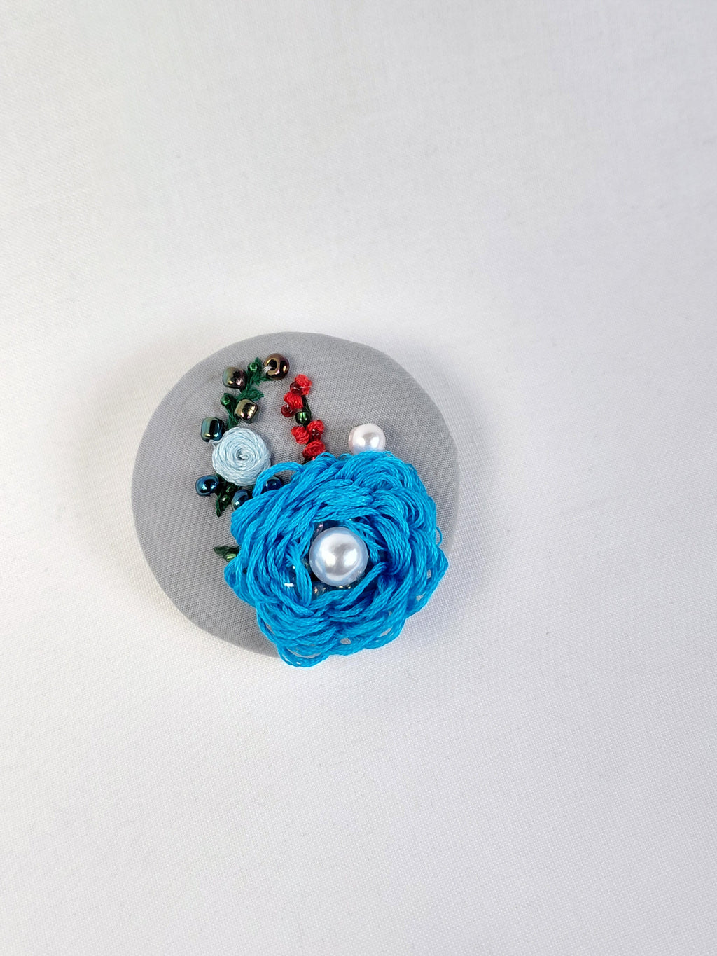 Decorative turquoise flower brooch on grey background