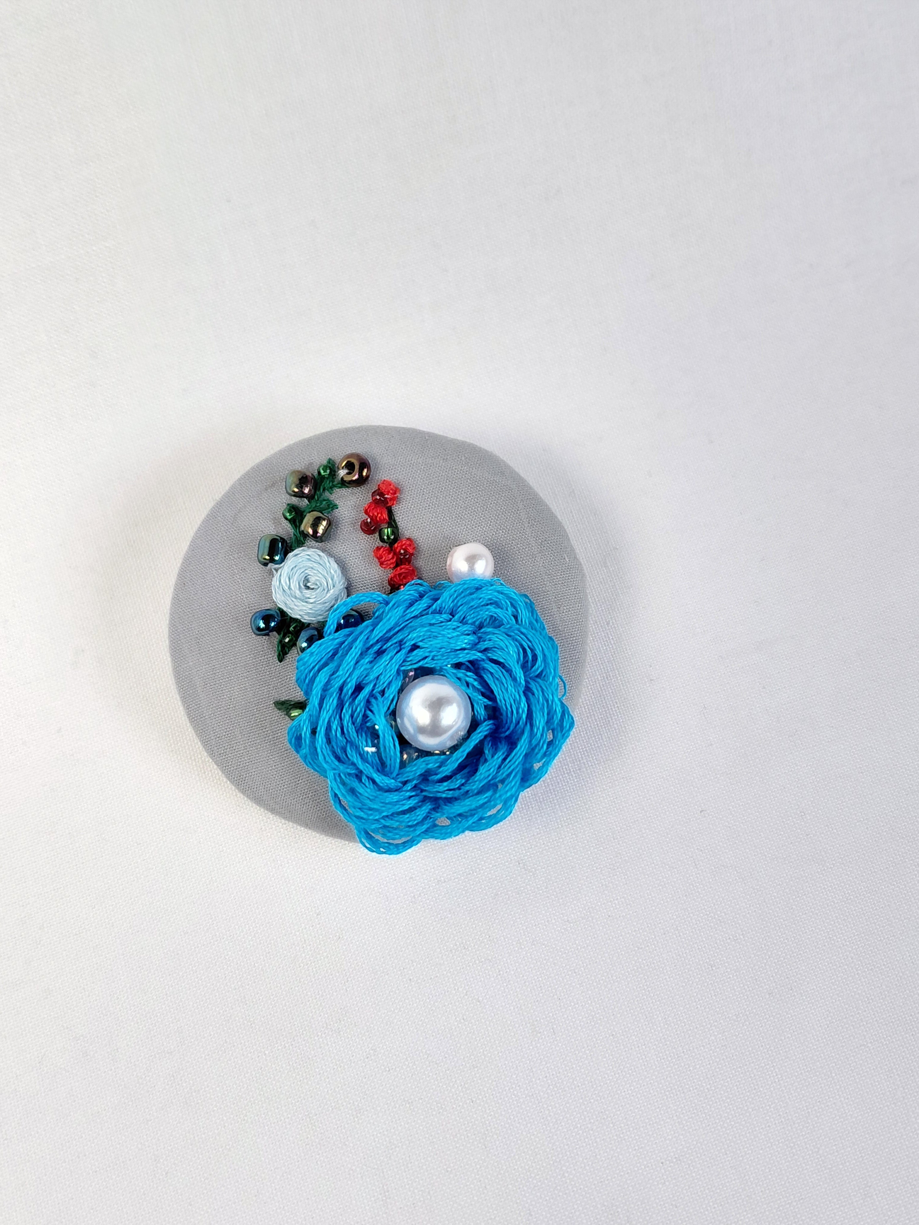 Decorative turquoise flower brooch on grey background