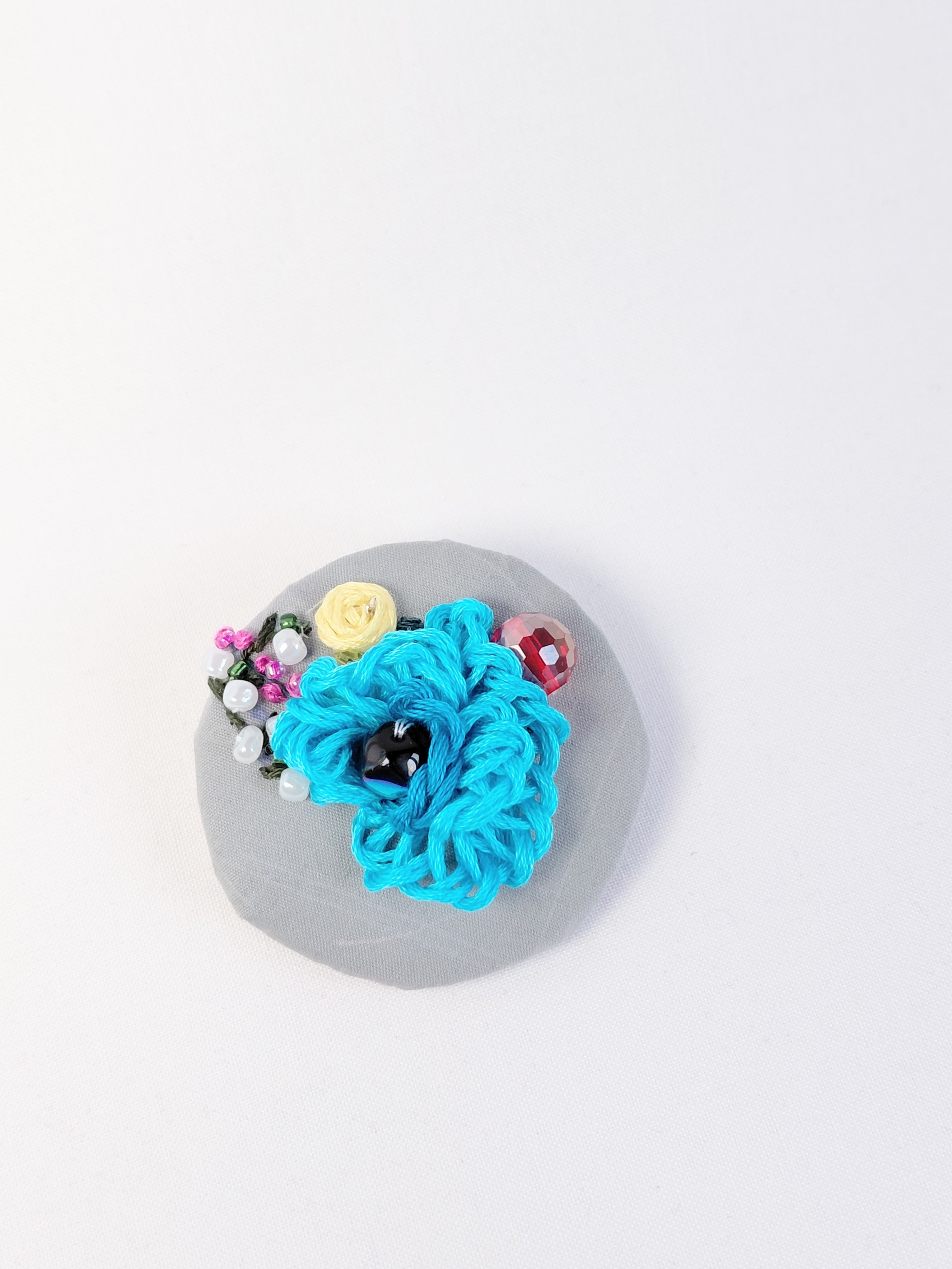 Decorative turquoise flower brooch on grey   background
