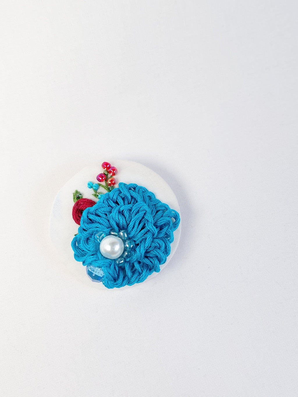Decorative turquoise flower brooch on white background