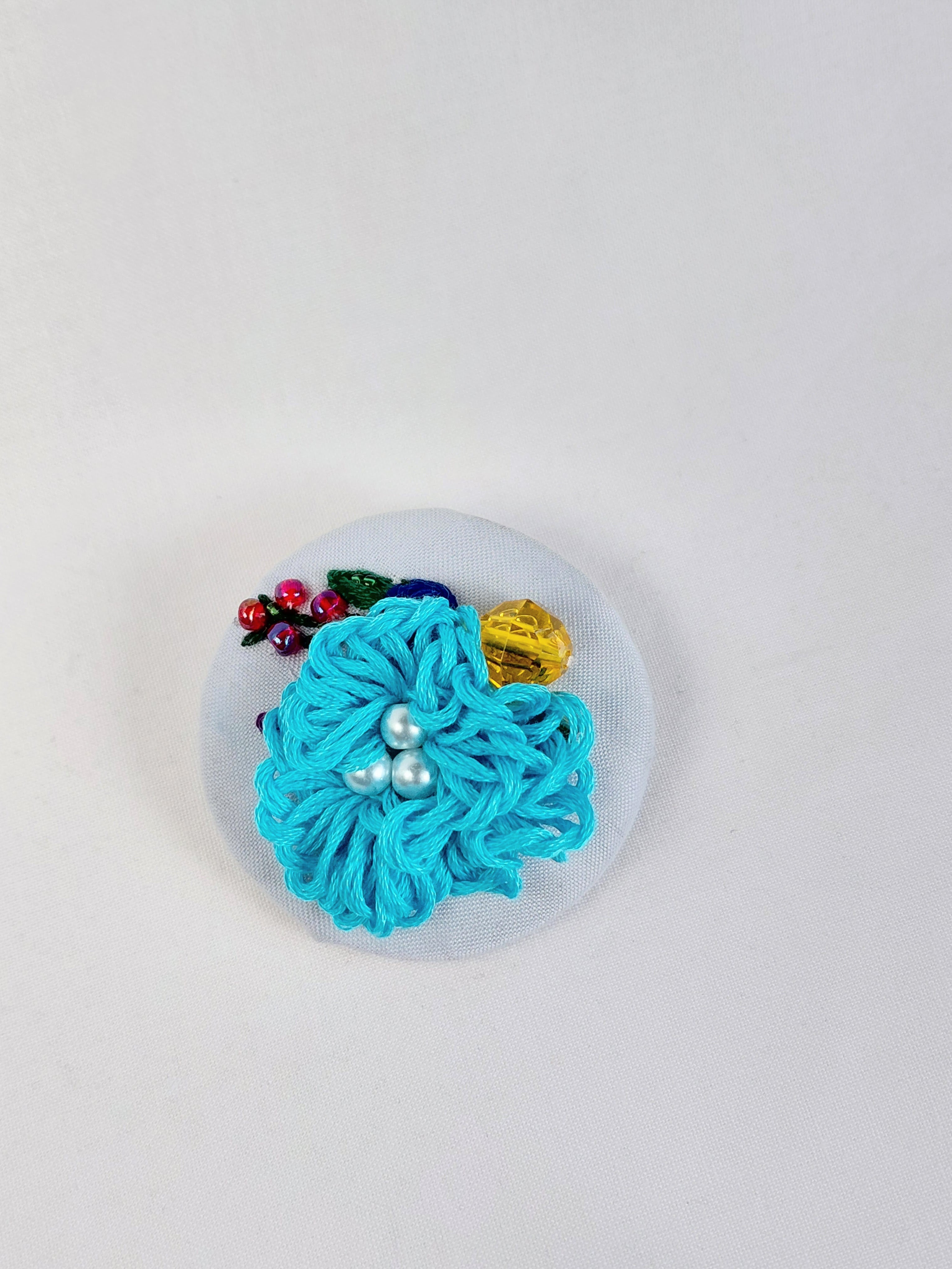 Decorative turquoise flower brooch on light blue background