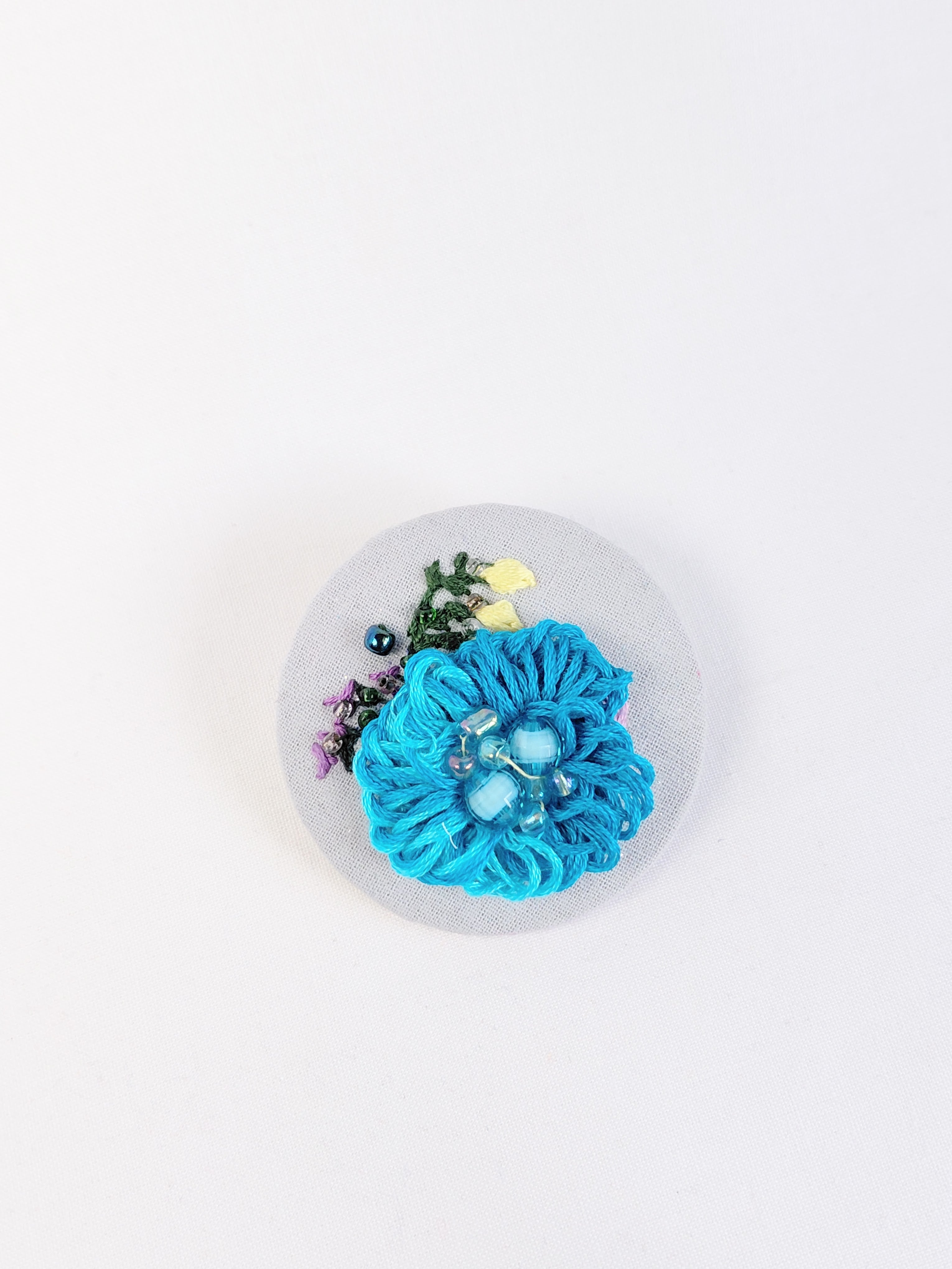 Decorative turquoise flower brooch on light blue background