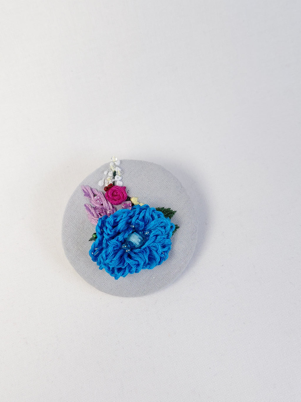 Decorative turquoise flower brooch on light blue with specs background