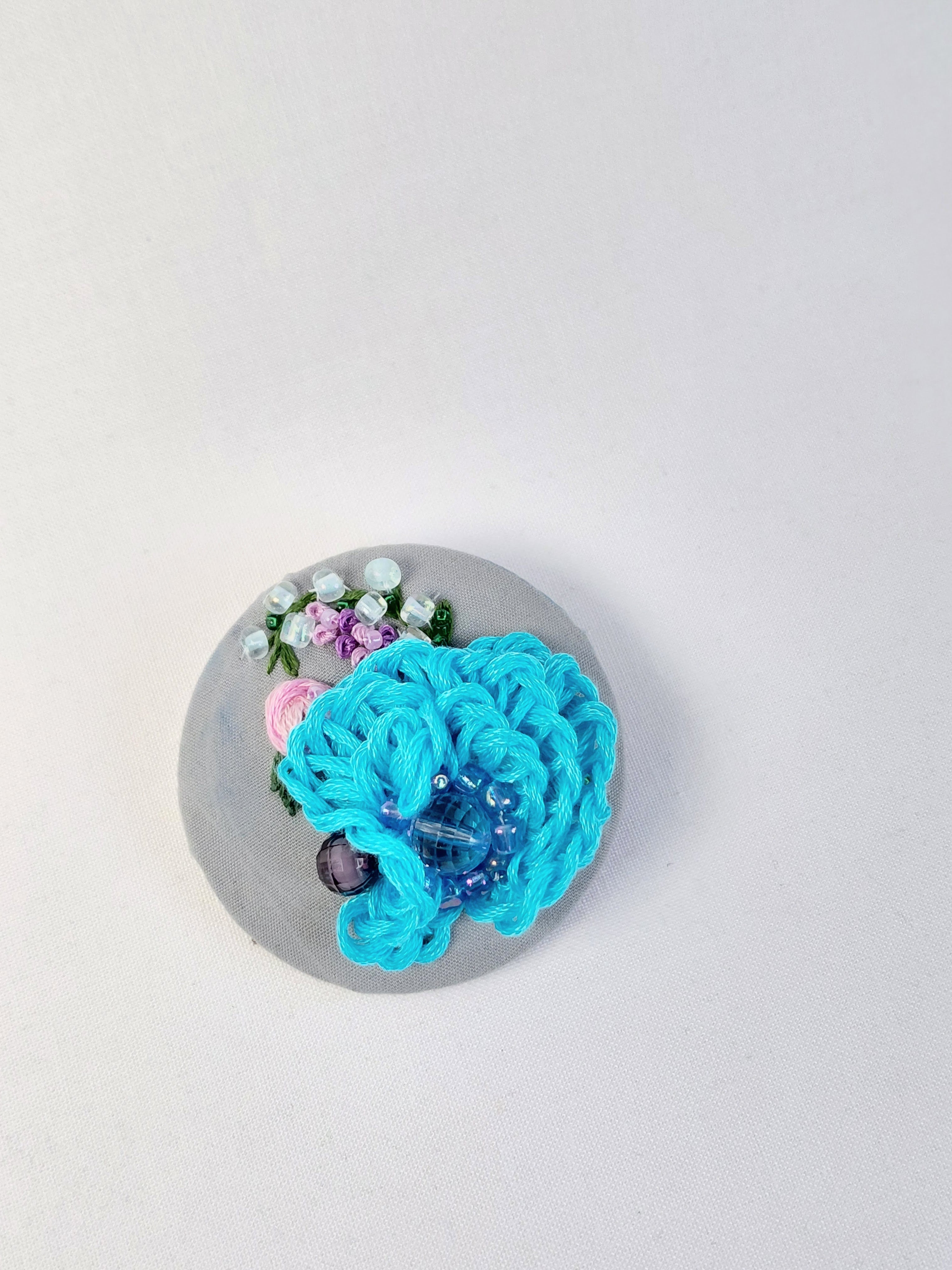 Decorative turquoise flower brooch on grey background