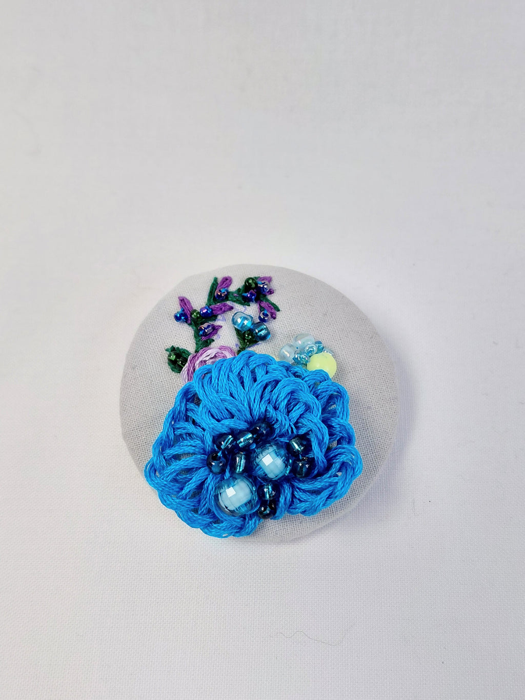 Decorative turquoise flower brooch on grey with specs background