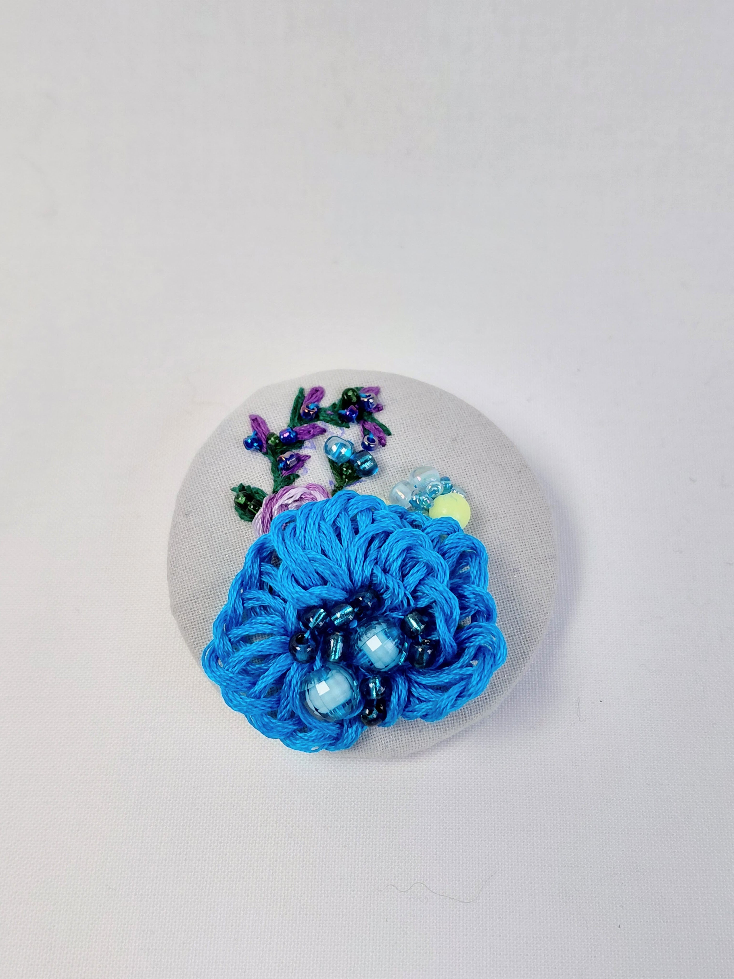 Decorative turquoise flower brooch on grey with specs background