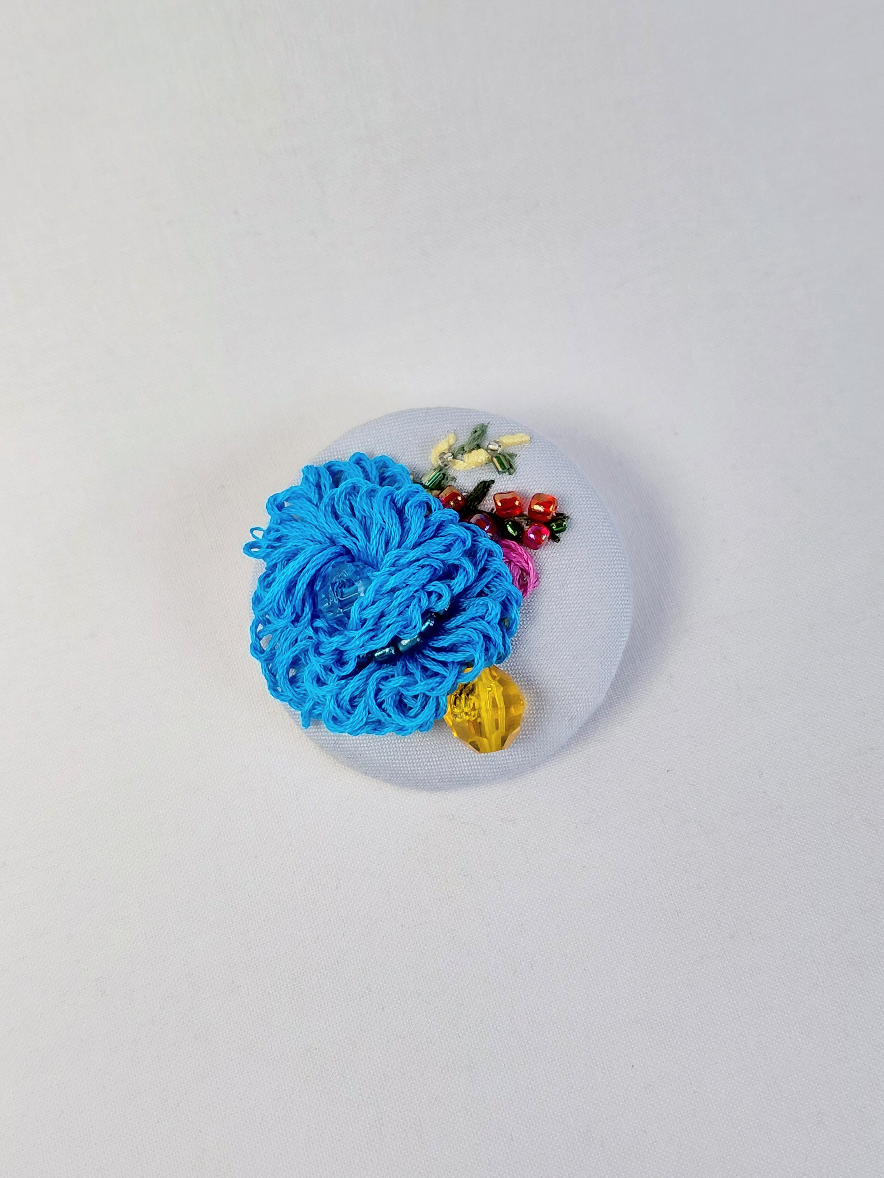 Decorative turquoise flower brooch on light blue background