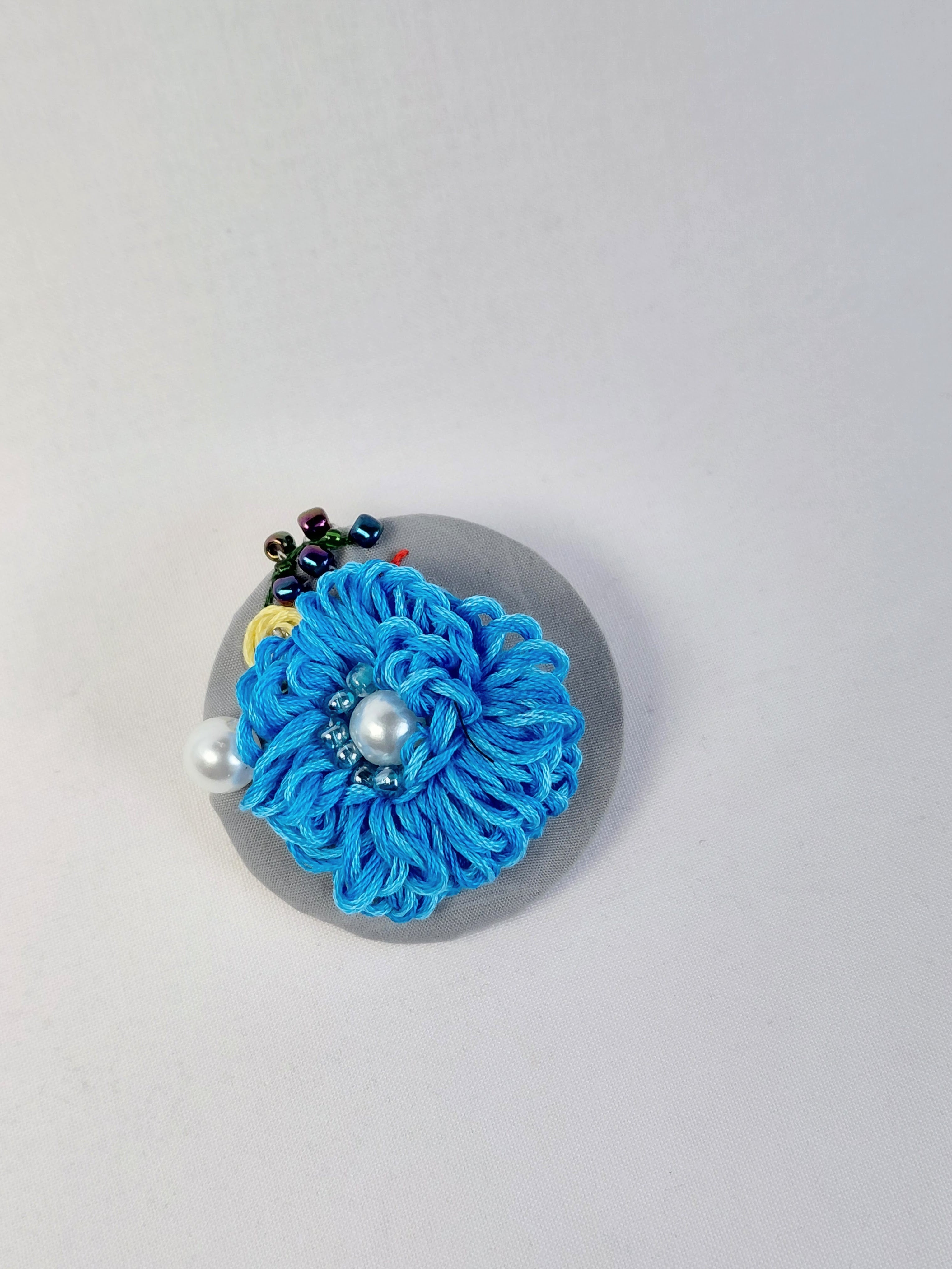 Decorative turquoise flower brooch on grey background