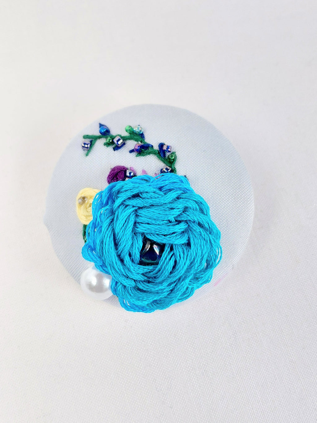 Decorative turquoise flower brooch on light blue background