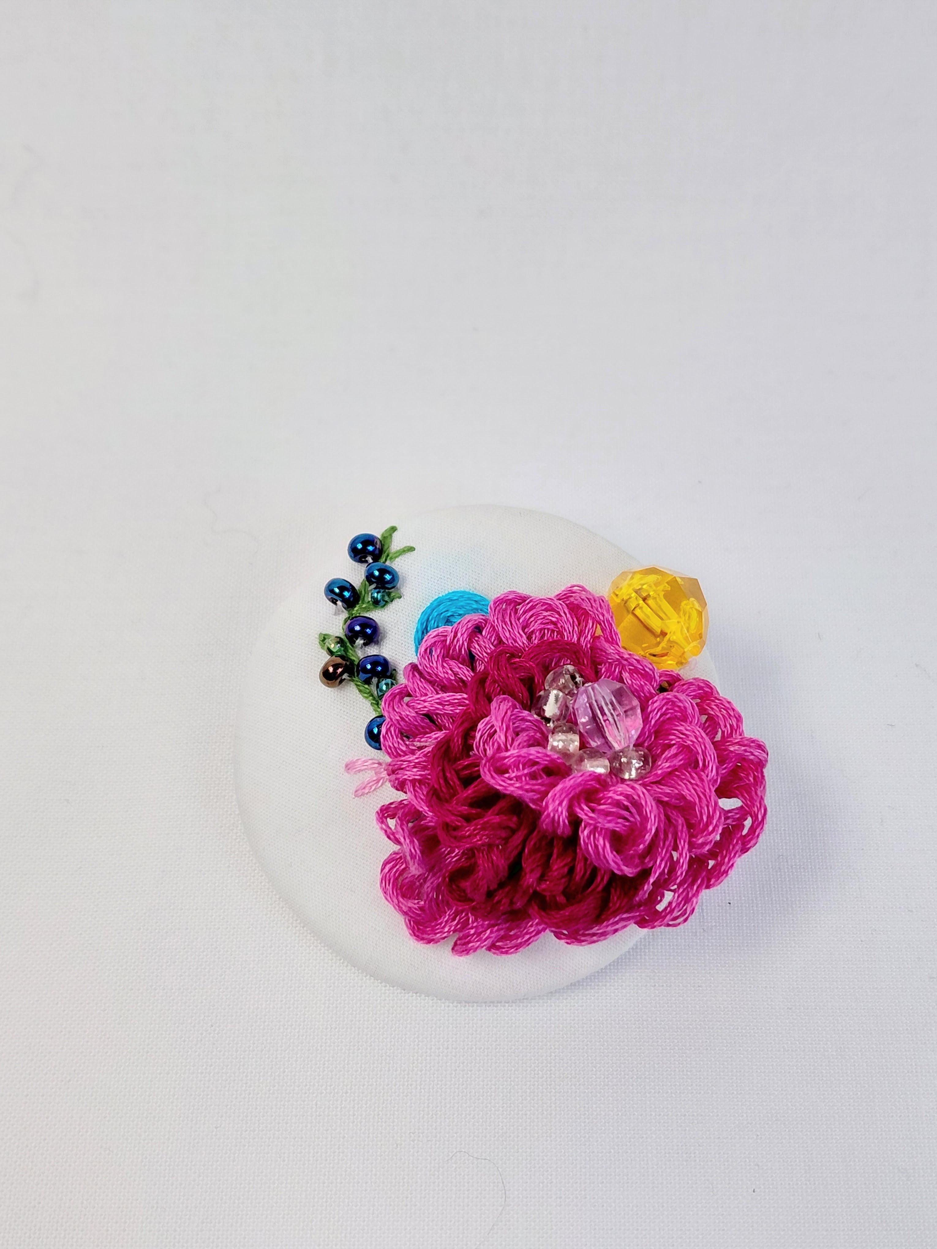 Decorative fuschia flower brooch on white background